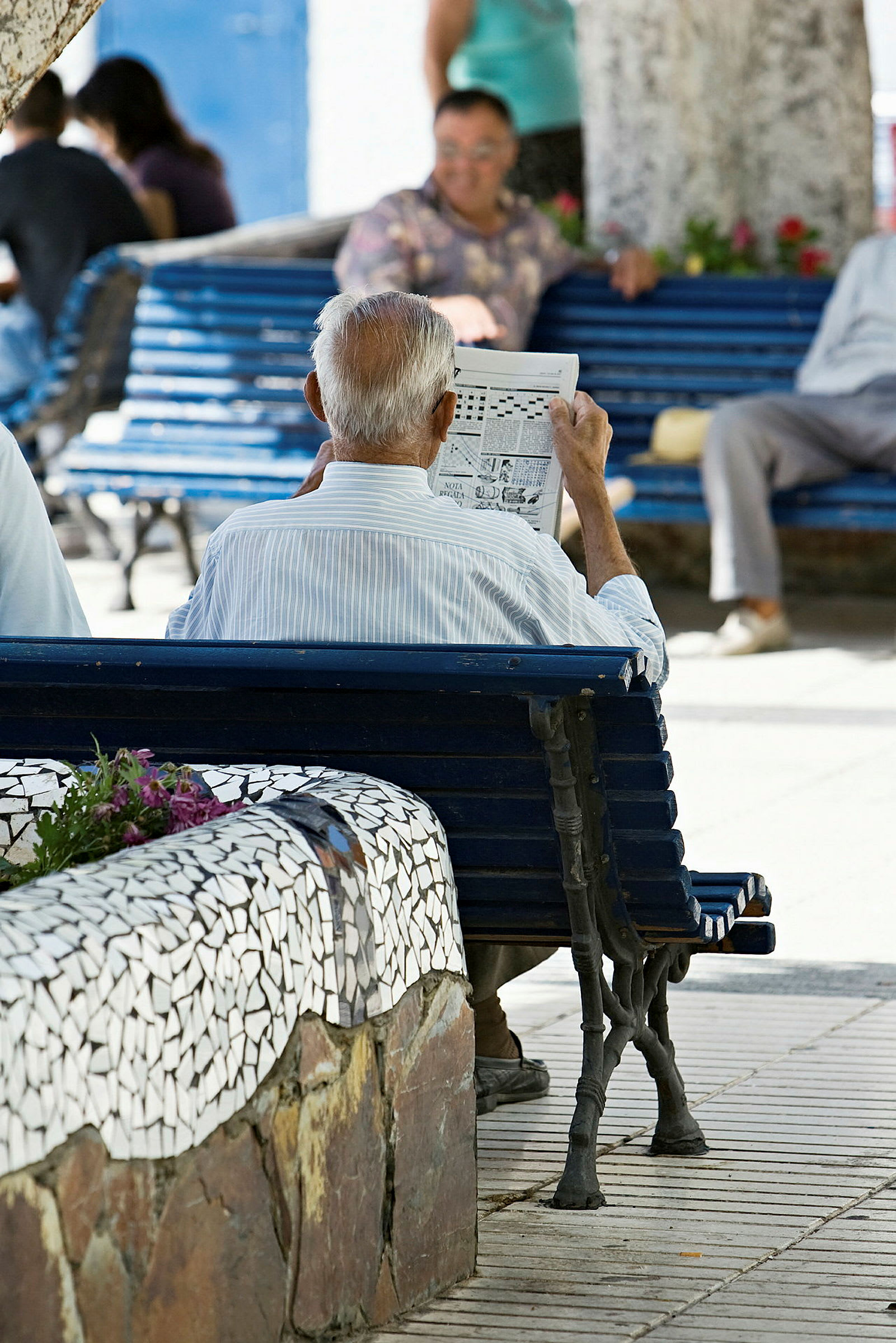 En äldre man sitter på en parkbänk och läser en tidning. (AI-genererad text)