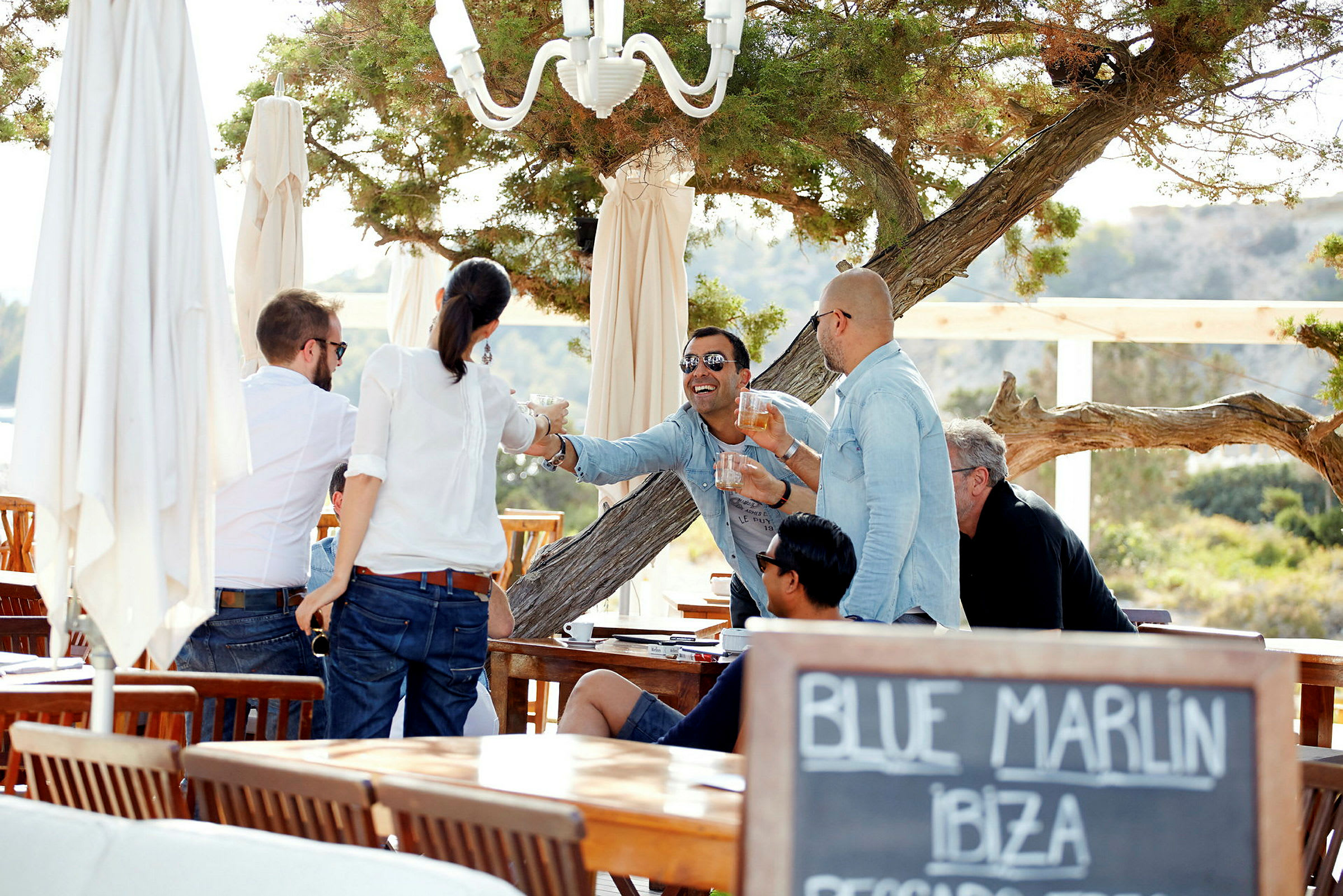 En grupp människor som interagerar och njuter av en måltid på en utomhusrestaurang. (AI-genererad text)
