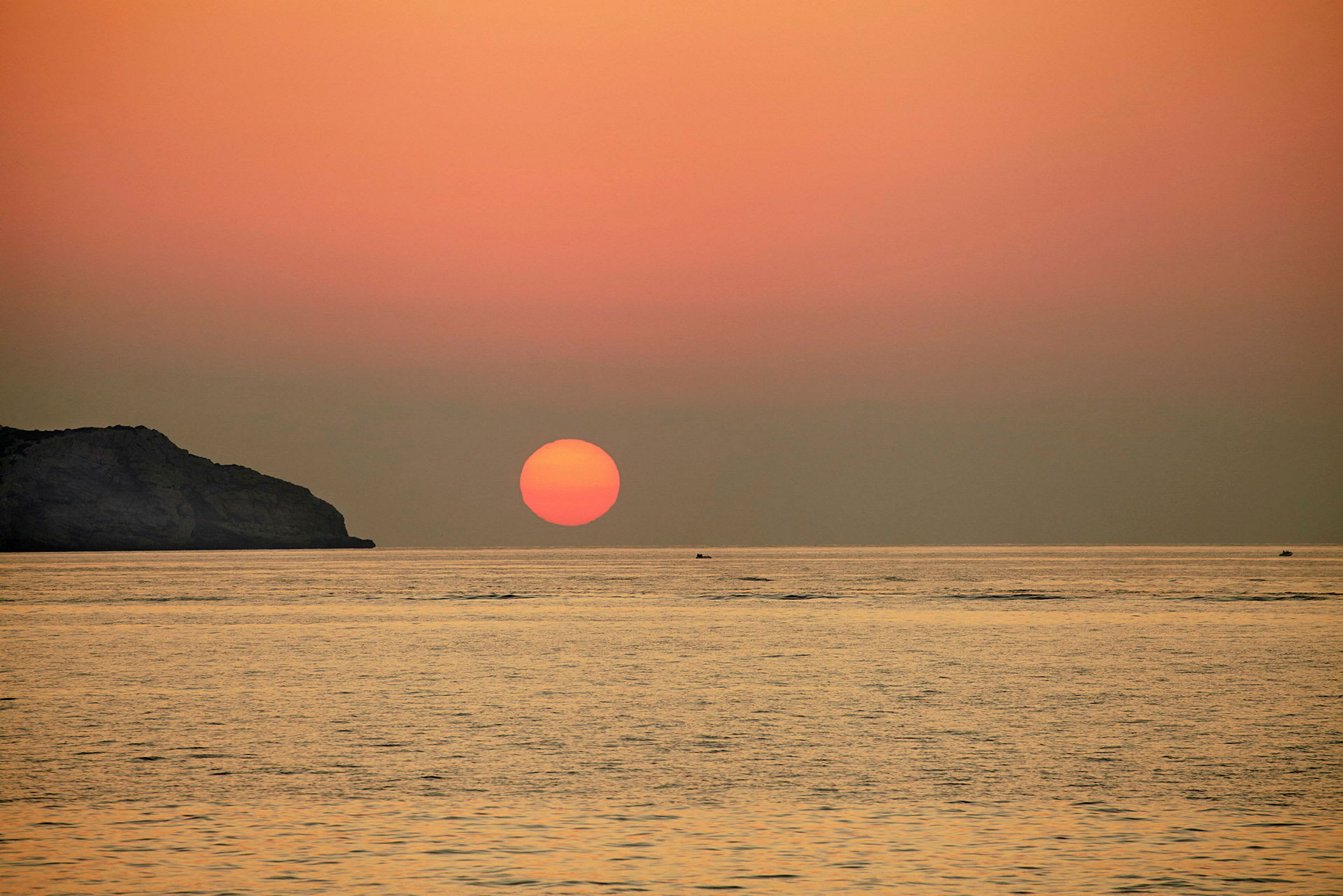 Bild av en solnedgång över havet med en klippformation till vänster. (AI-genererad text)