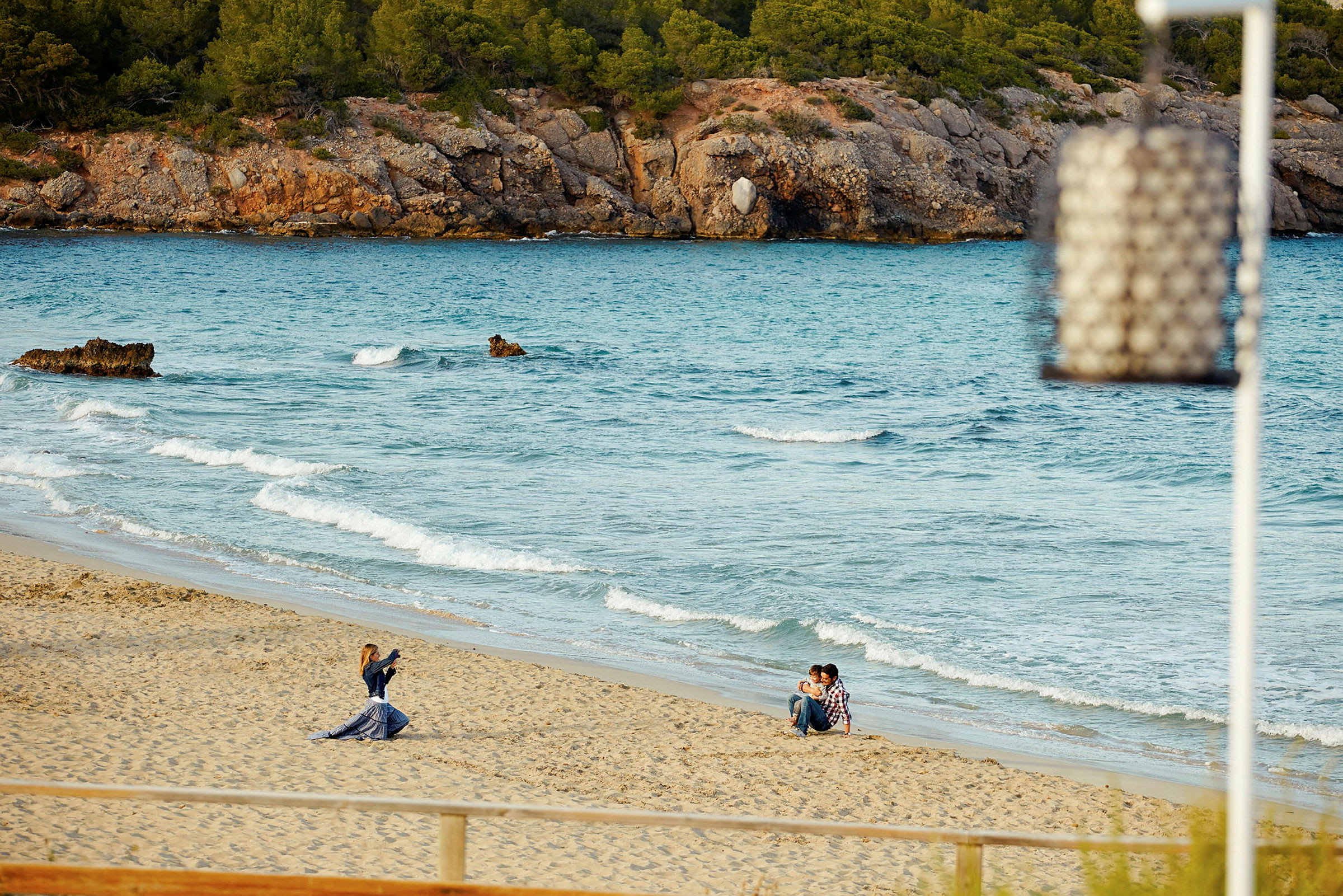 En sandstrand med vågor och en fotograf som tar bilder av ett par. (AI-genererad text)