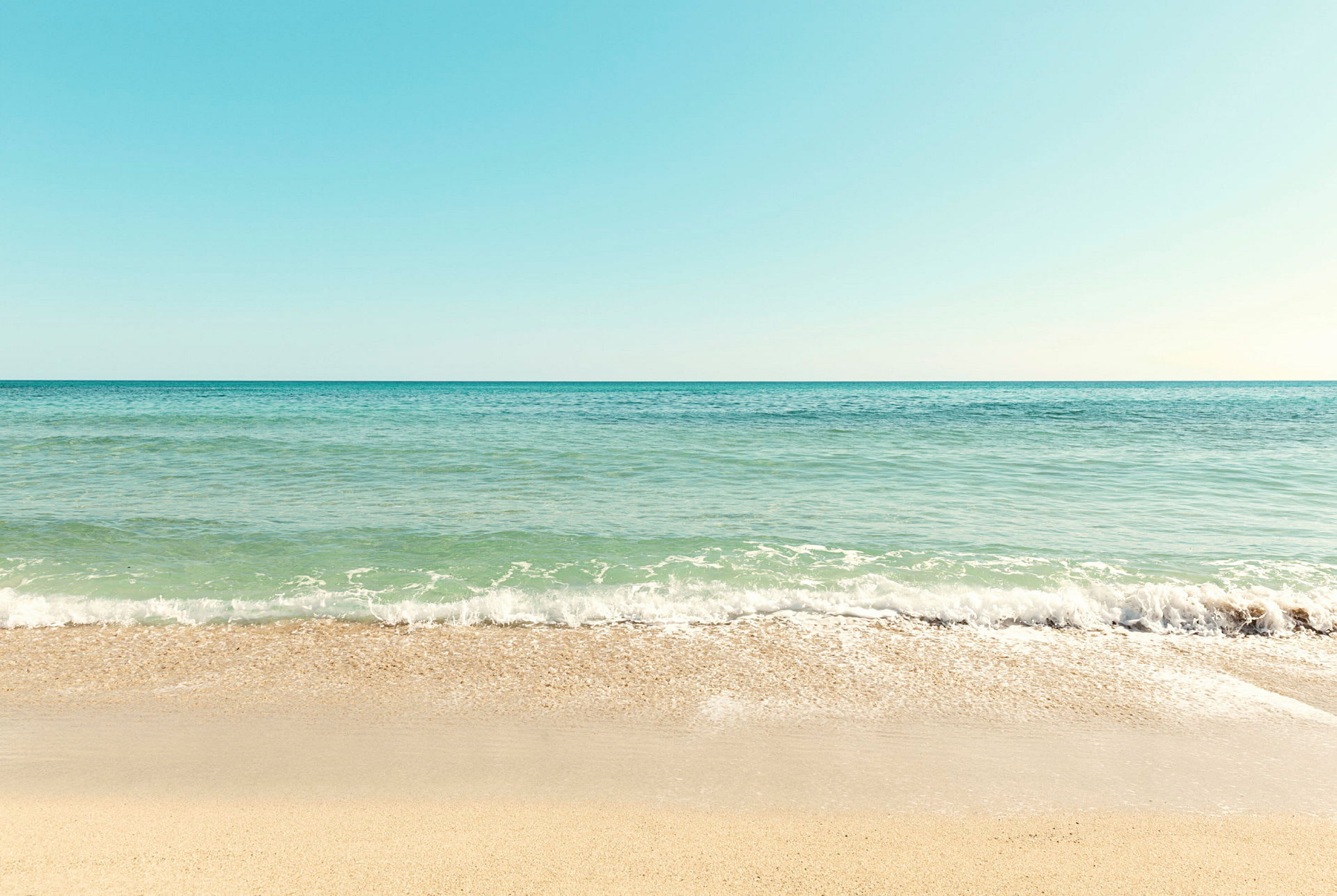 En strand med sand och havet som möter himlen. (AI-genererad text)