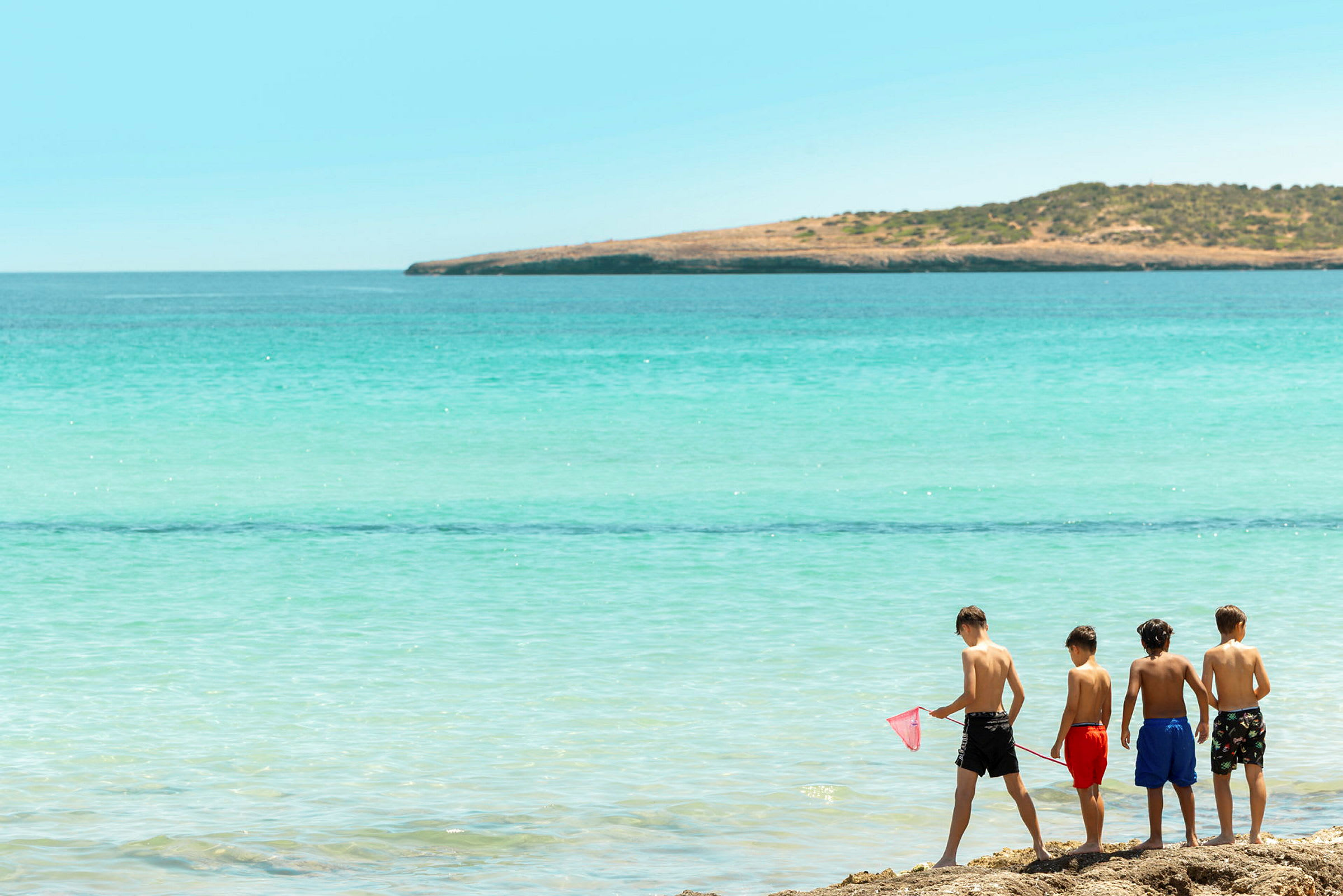 Fyra barn står på stranden och blickar ut mot havet. (AI-genererad text)