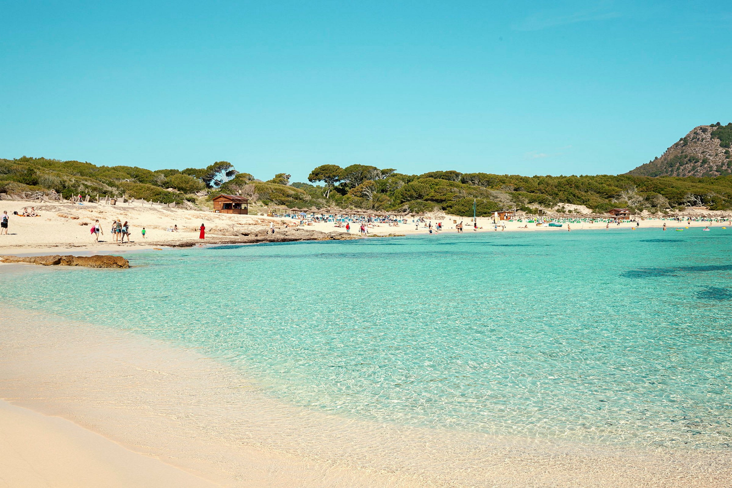 En strand med klarblått vatten och människor som njuter av solen. (AI-genererad text)