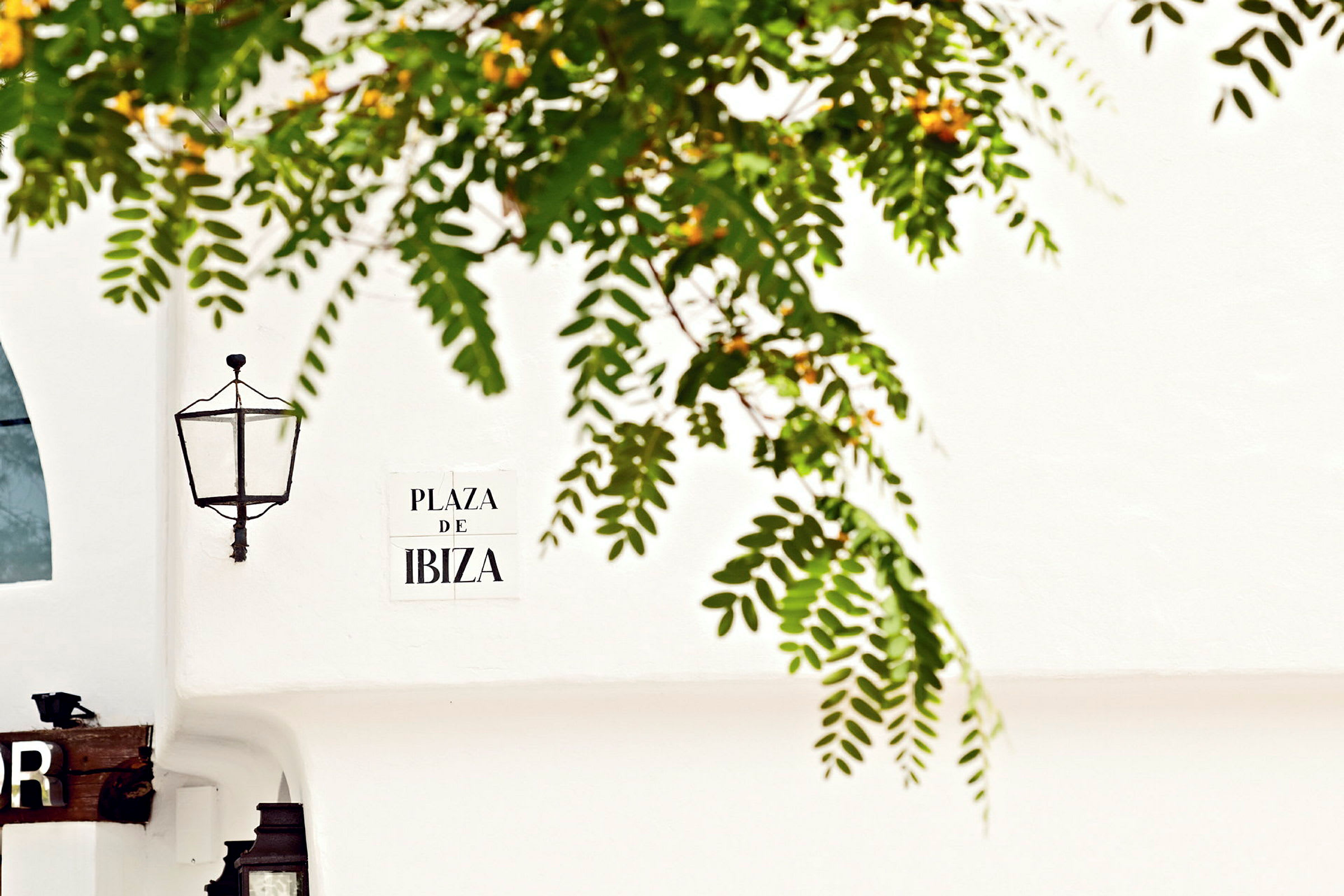 En vägg med en lampa och en skylt med texten 'Plaza De Ibiza'. (AI-genererad text)