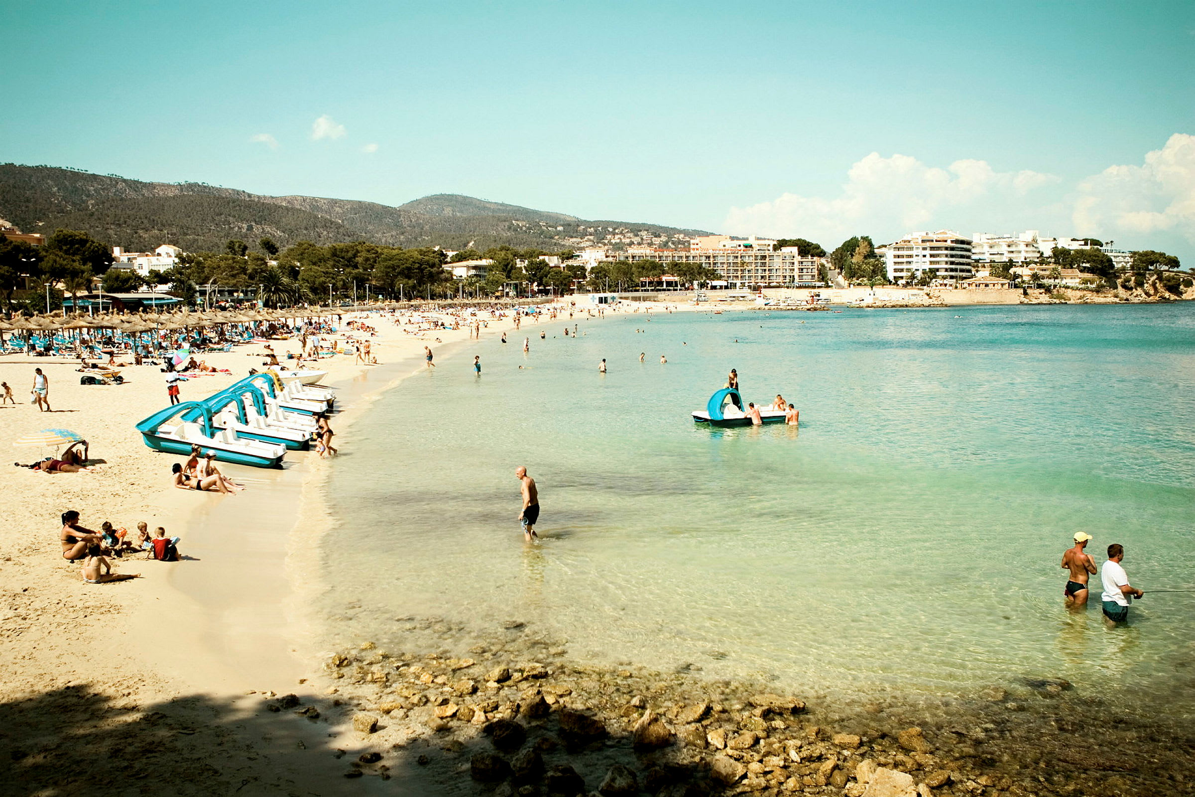 Strand med turkost vatten och semesterfirare. (AI-genererad text)