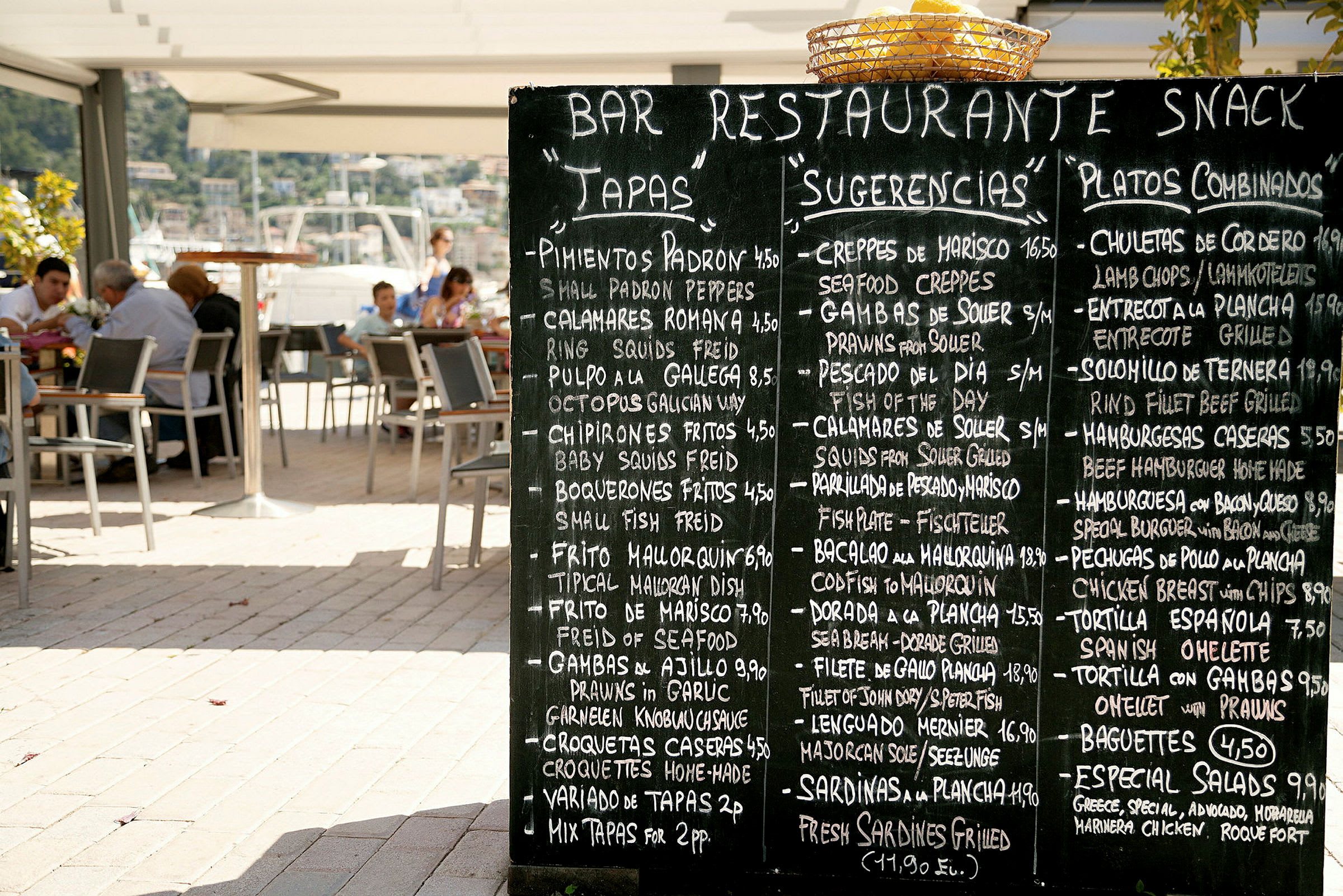 Svart griffeltavla med en meny vid en restaurangterrass. (AI-genererad text)
