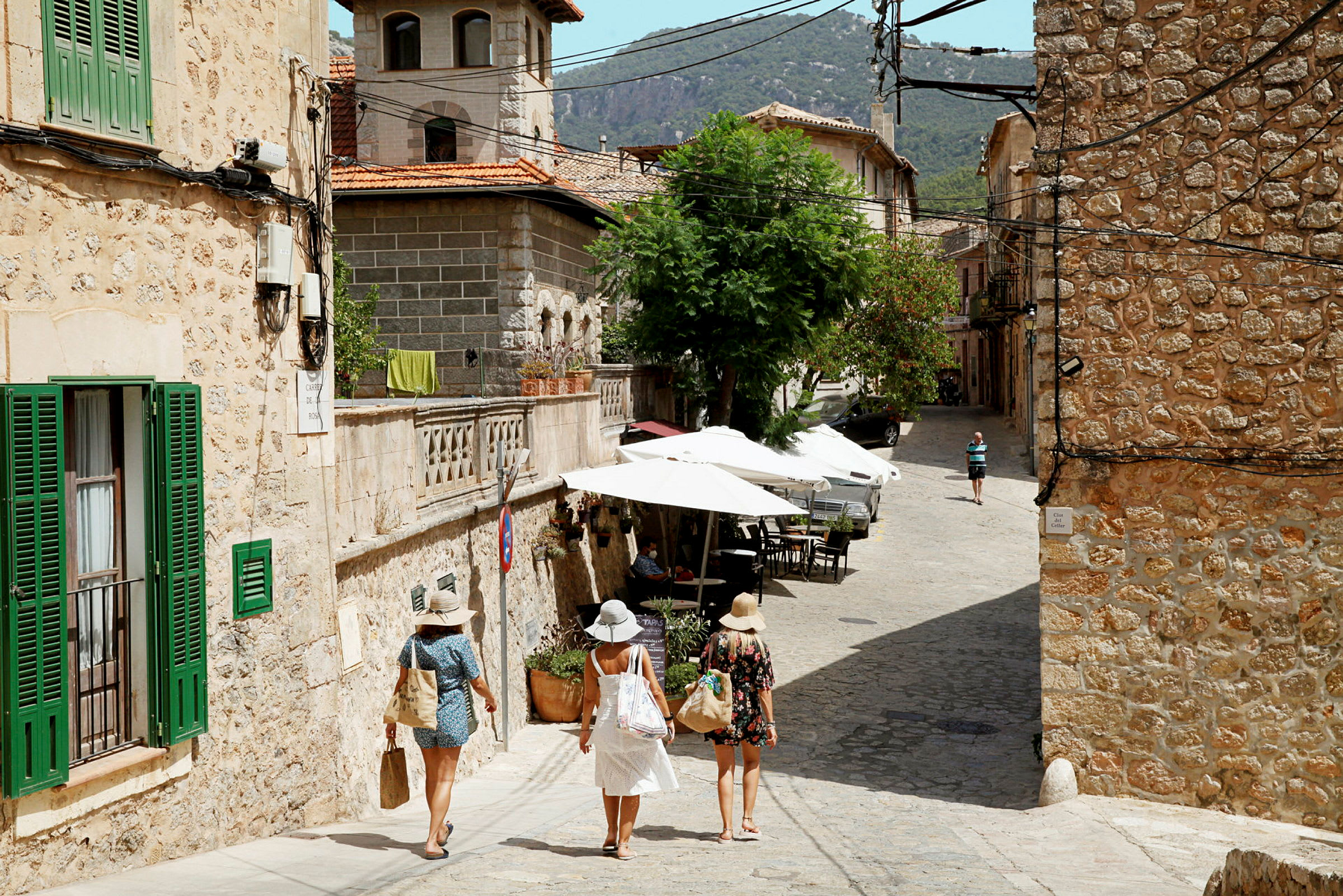 Tre personer promenerar längs en stenlagd gata i en pittoresk stad. (AI-genererad text)