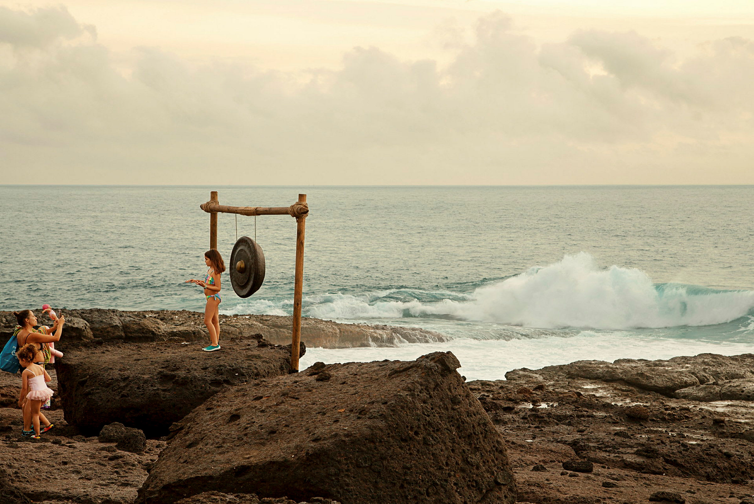 En gongong placerad nära havet, omgiven av stenar. (AI-genererad text)