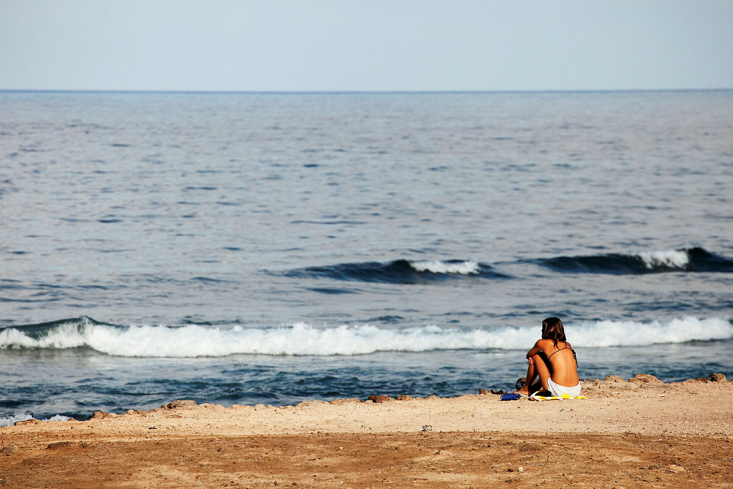 En person sitter på en strand nära havet. (AI-genererad text)