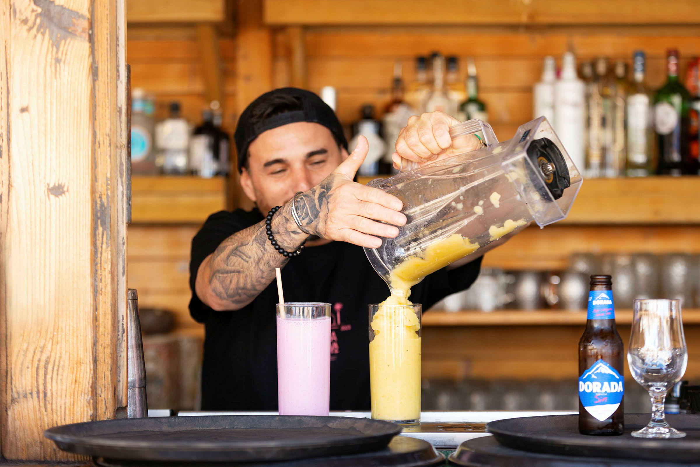 Någon häller gul dryck från en mixer till ett glas på en bänkskiva. (AI-genererad text)