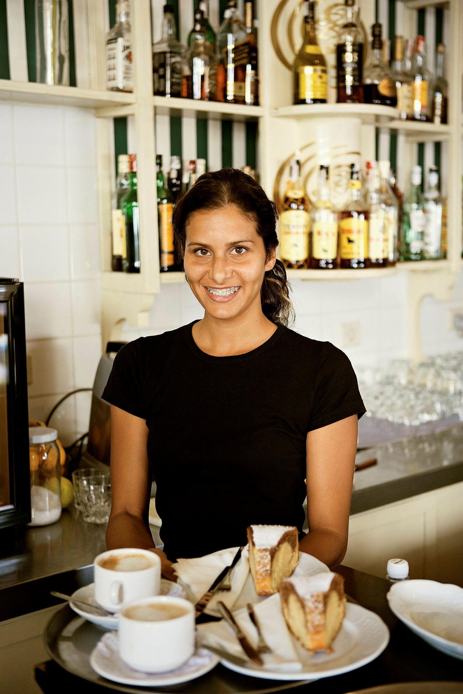 En serveringsbricka med två koppar kaffe och två bitar kaka placerad på ett bord framför en bar. (AI-genererad text)