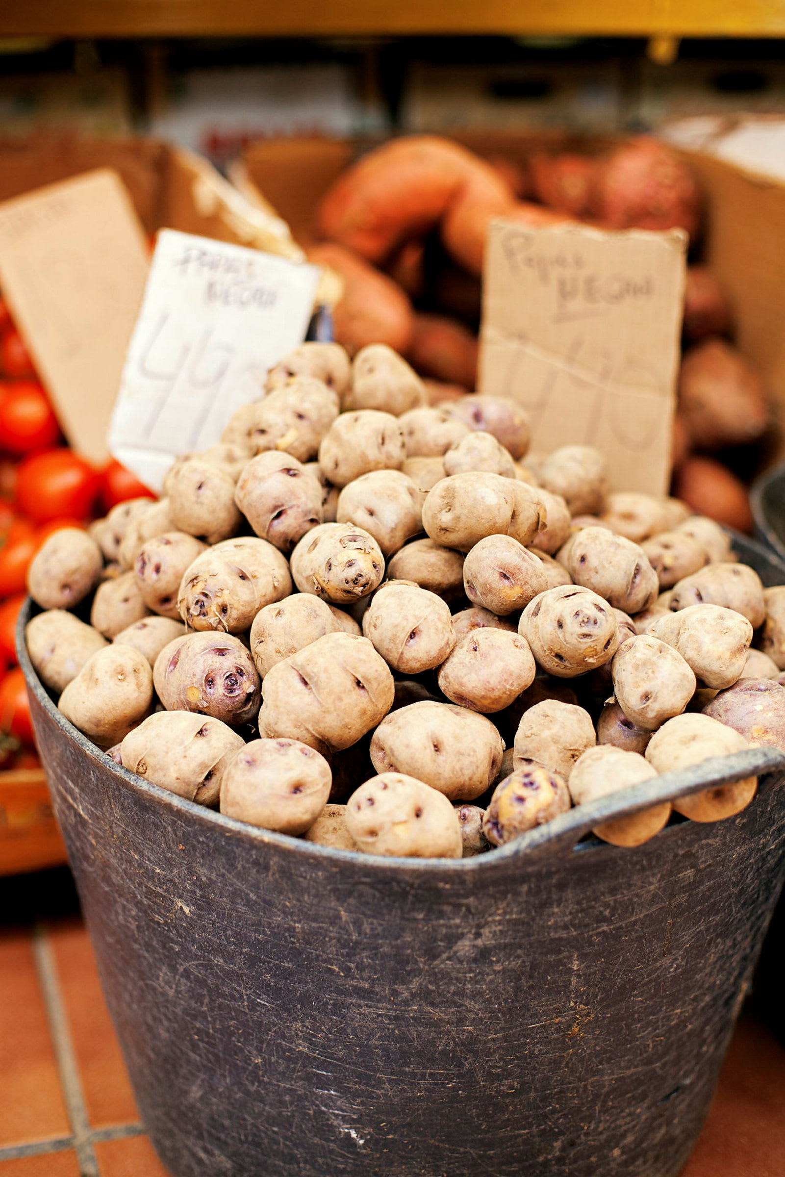 En hink fylld med potatis på en marknad. (AI-genererad text)