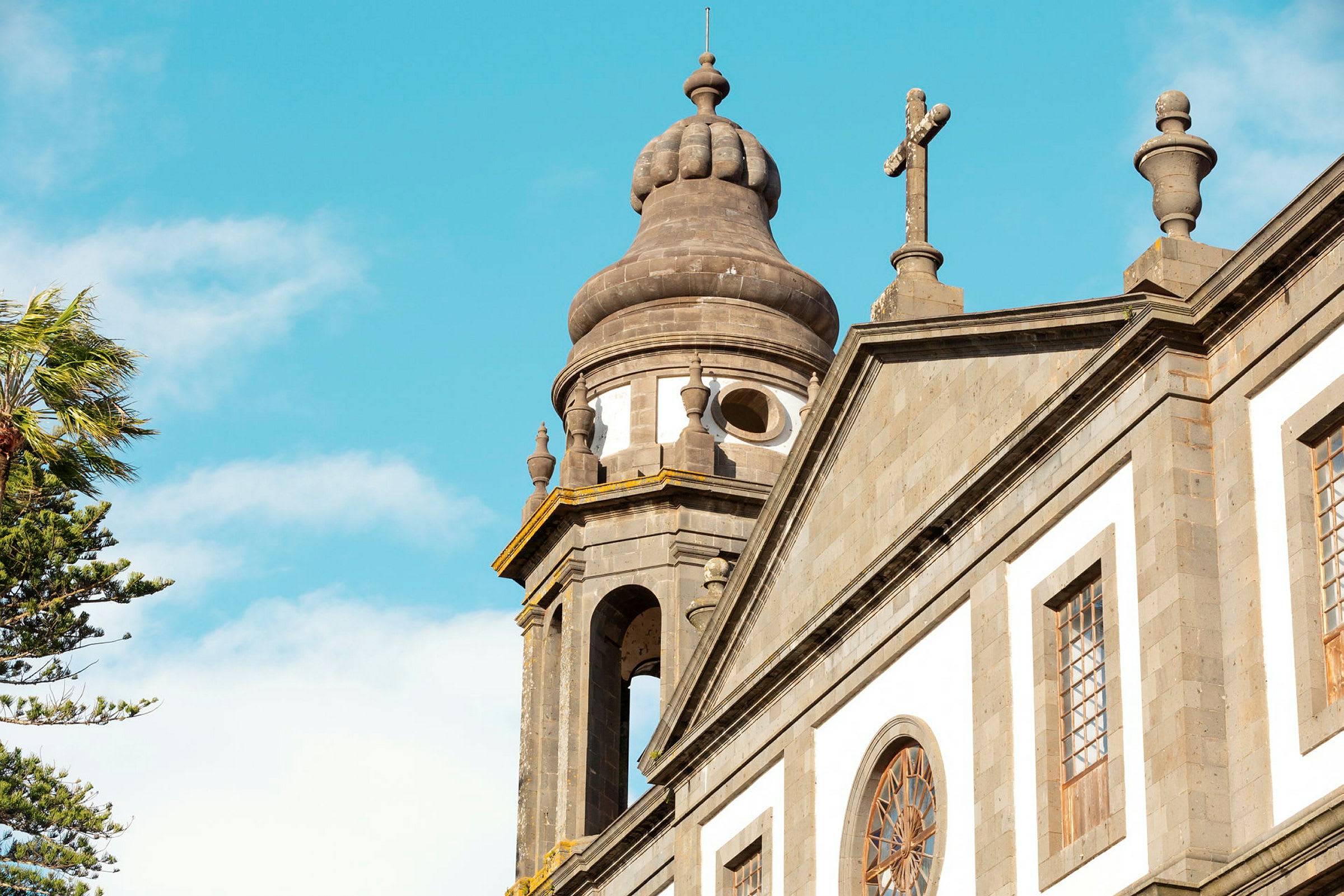 Närbild av en kyrka med detaljer på kupol och kors mot klarblå himmel. (AI-genererad text)