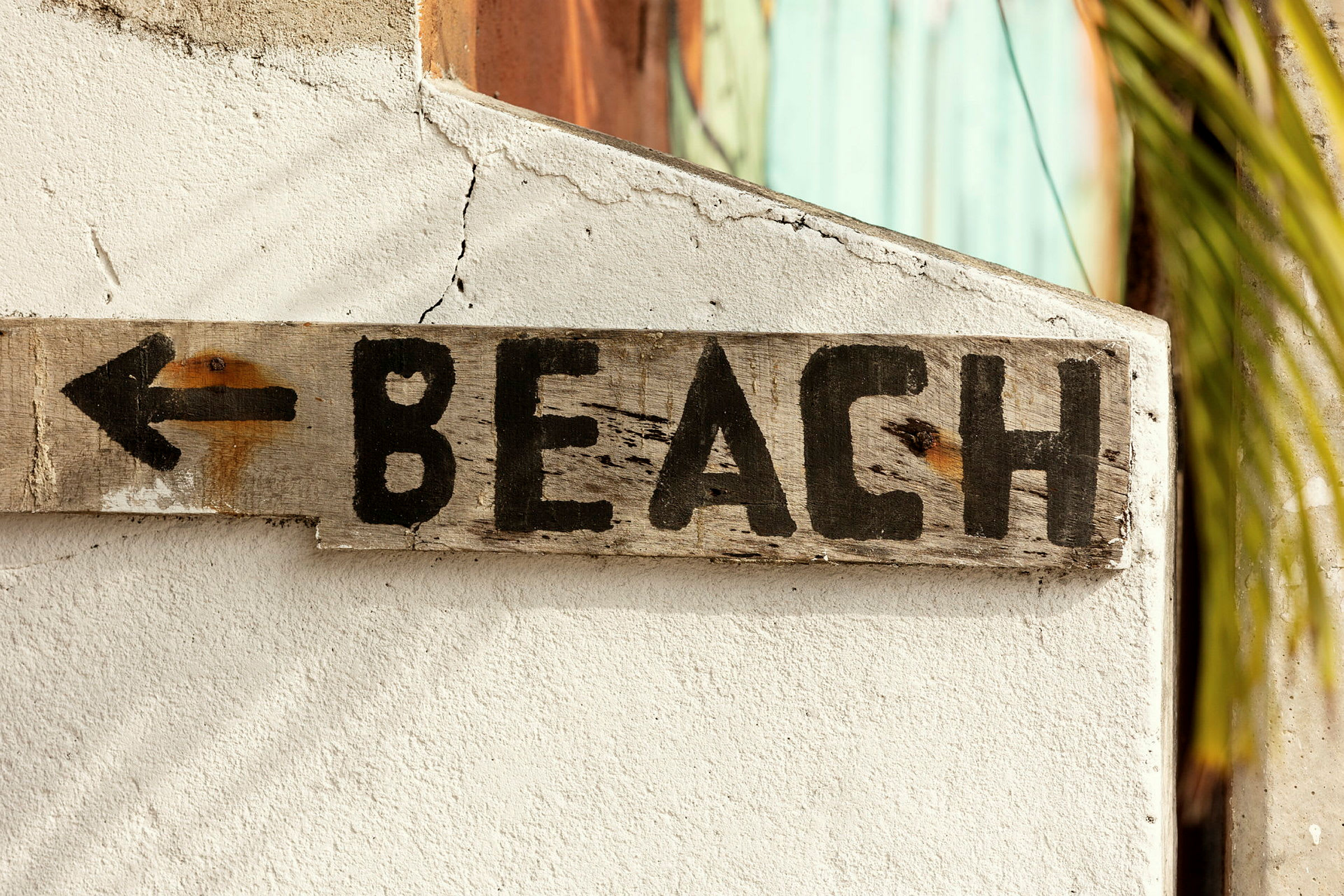 En träskylt med texten "BEACH" och en pil pekar till vänster. (AI-genererad text)