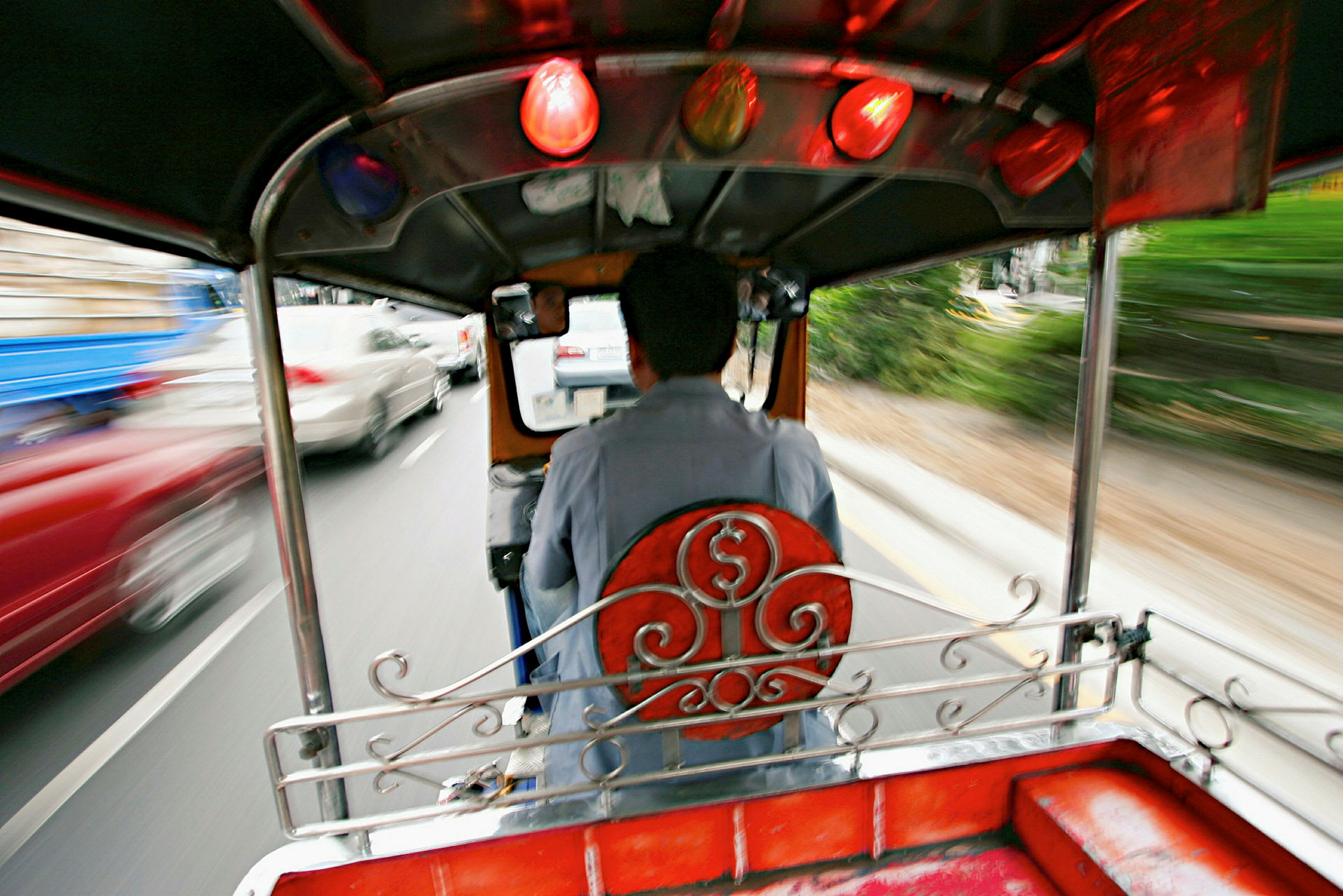 En förare kör en tuk-tuk på en trafikerad väg. (AI-genererad text)