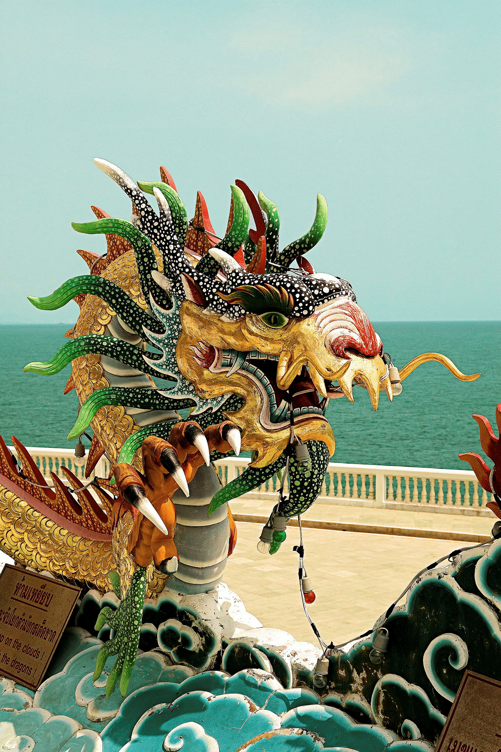Färgglad dragonstaty vid en strandpromenad. (AI-genererad text)