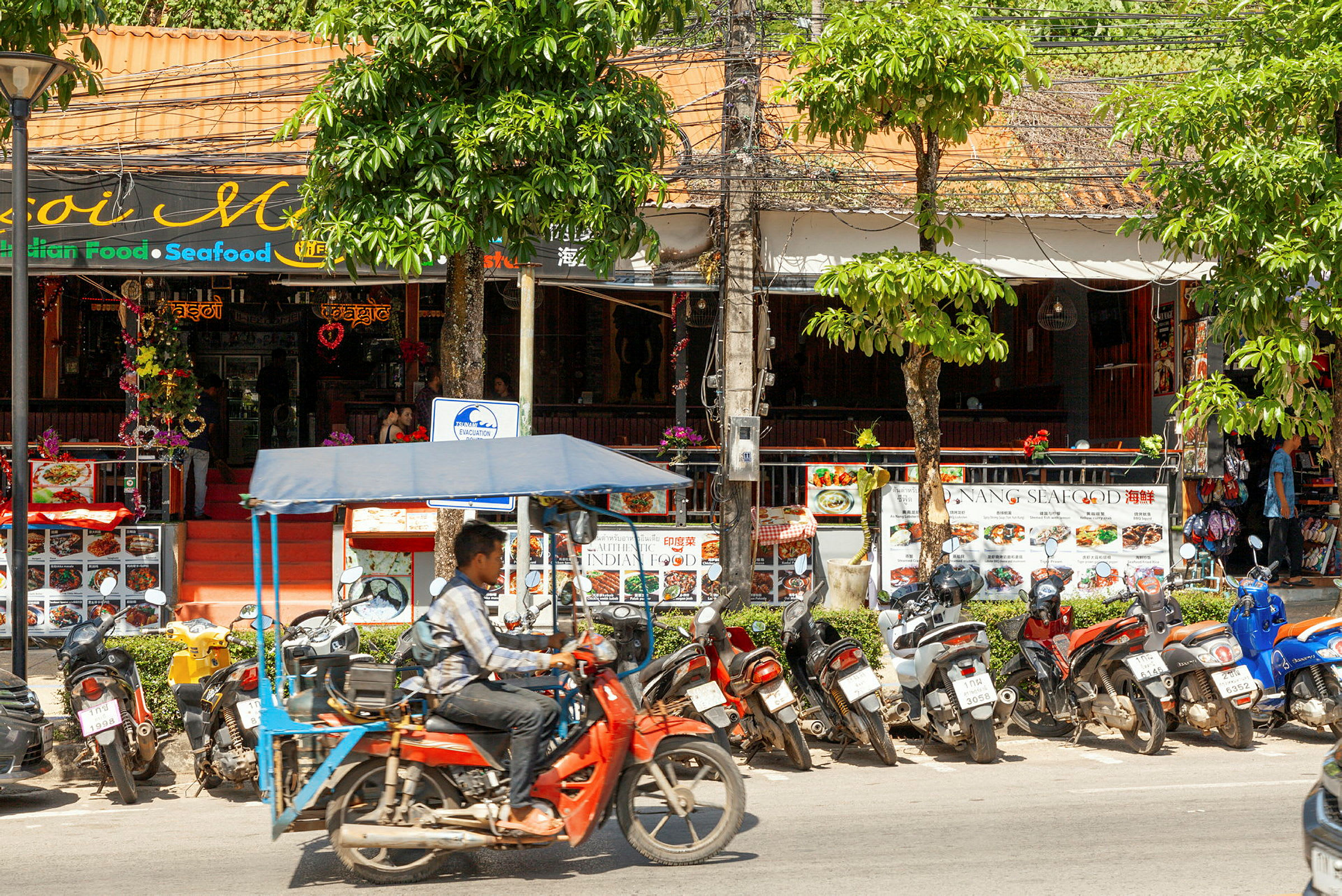 En gatumiljö med motorcyklar parkerade framför en restaurang. (AI-genererad text)
