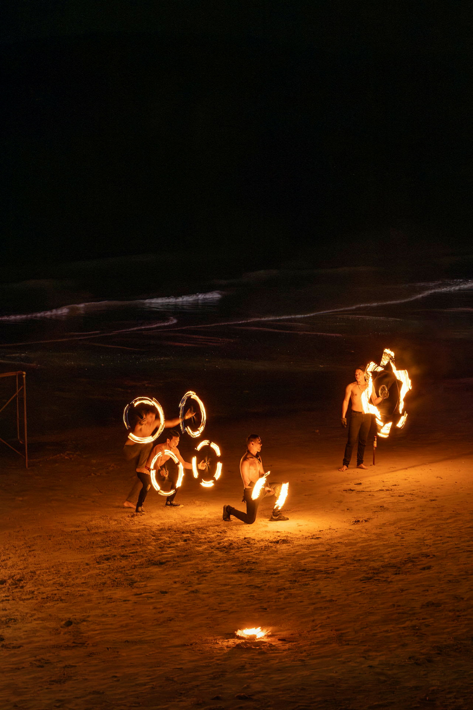 Personer utför en eldshow på en sandstrand under natten. (AI-genererad text)
