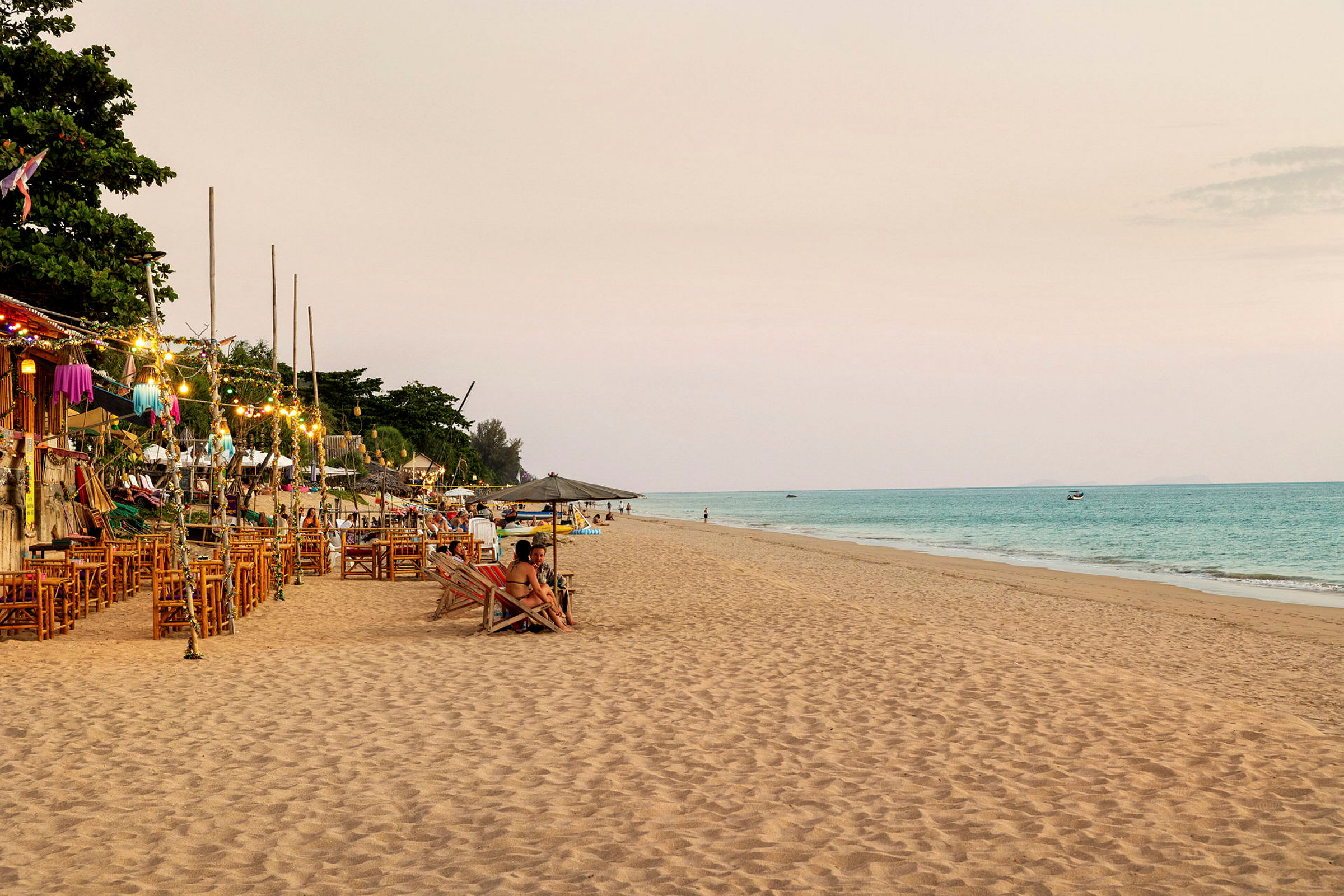 En strand med sand, hav och restauranger med uteserveringar. (AI-genererad text)