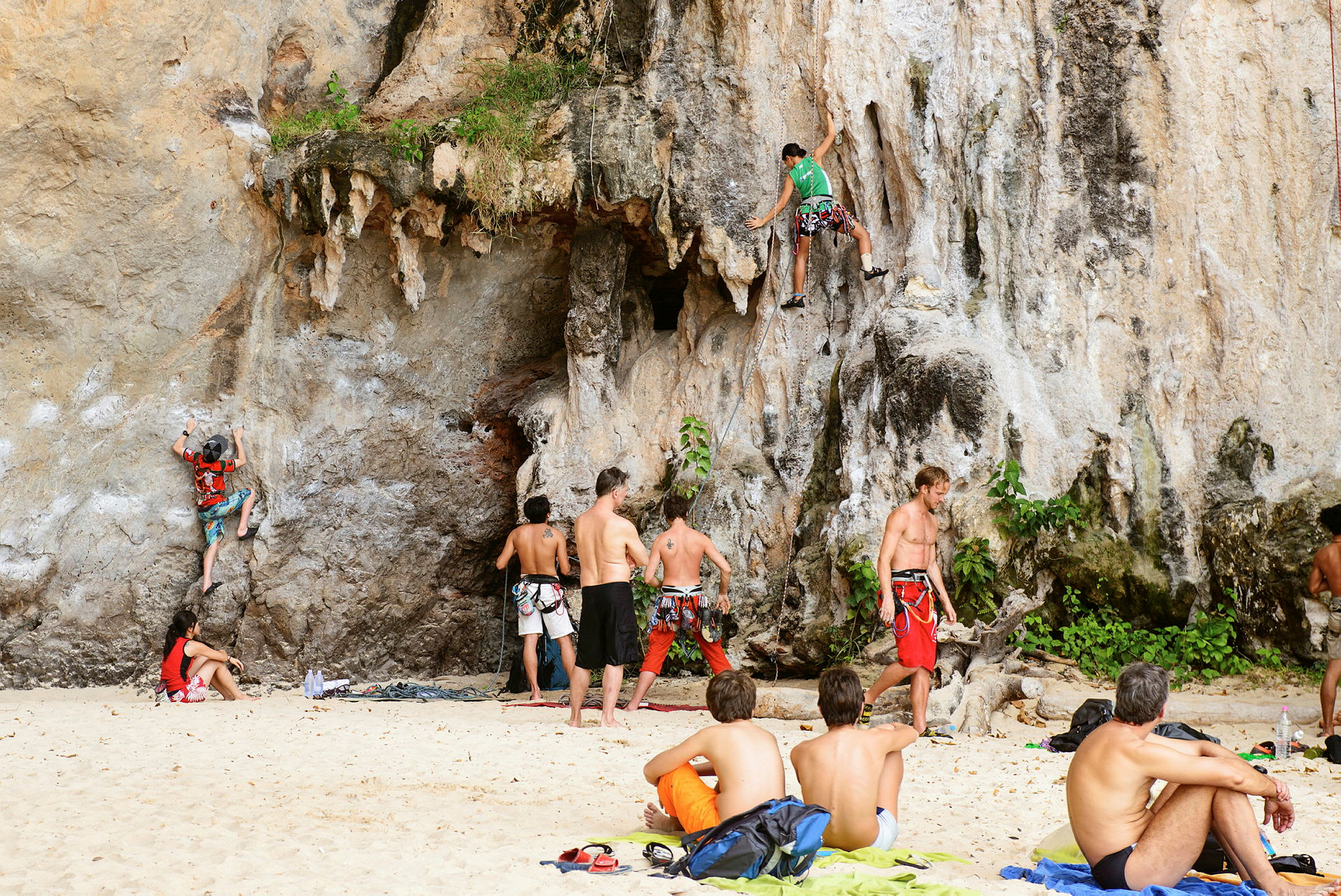 Personer klättrar på klippa vid en strand. (AI-genererad text)