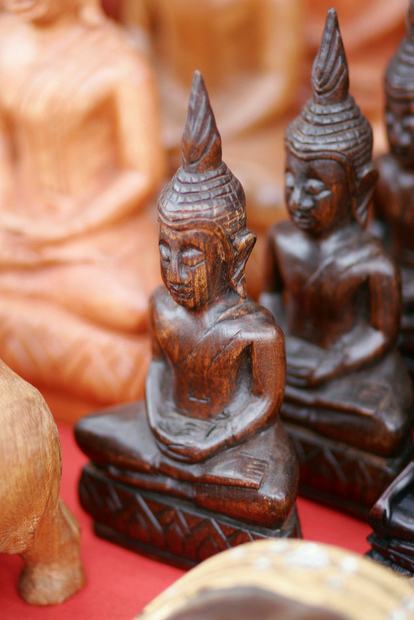 Bild av en samling små, träsnidna buddhastatyer framför en röd bakgrund. (AI-genererad text)