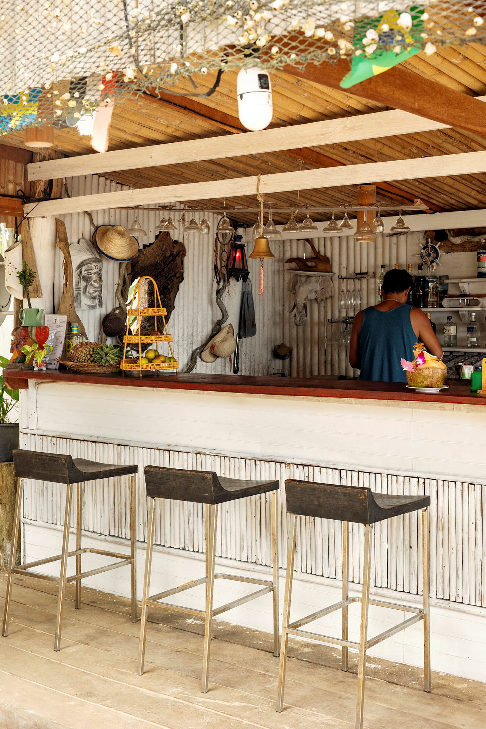 Bild av en strandbar med tre pallar, dekorationer på väggen och en person vid disken. (AI-genererad text)