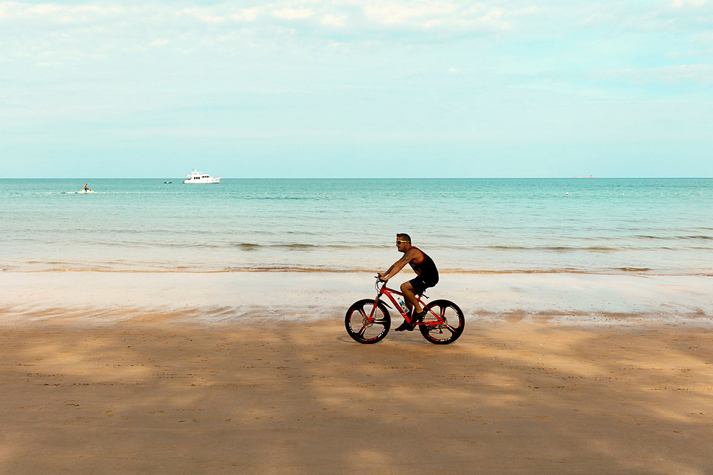 En person cyklar vid en sandstrand med havet i bakgrunden. (AI-genererad text)