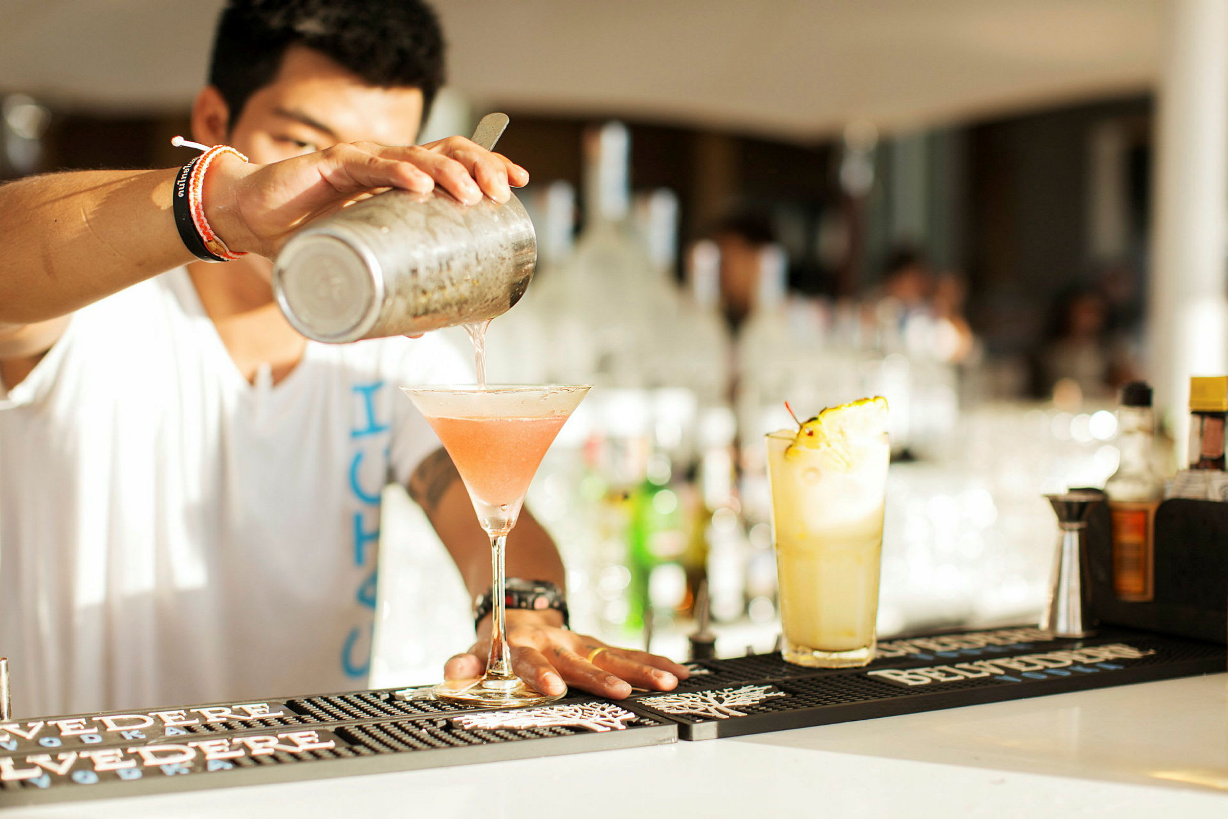 En cocktail blandas och hälls upp i ett glas på en bardisk. (AI-genererad text)