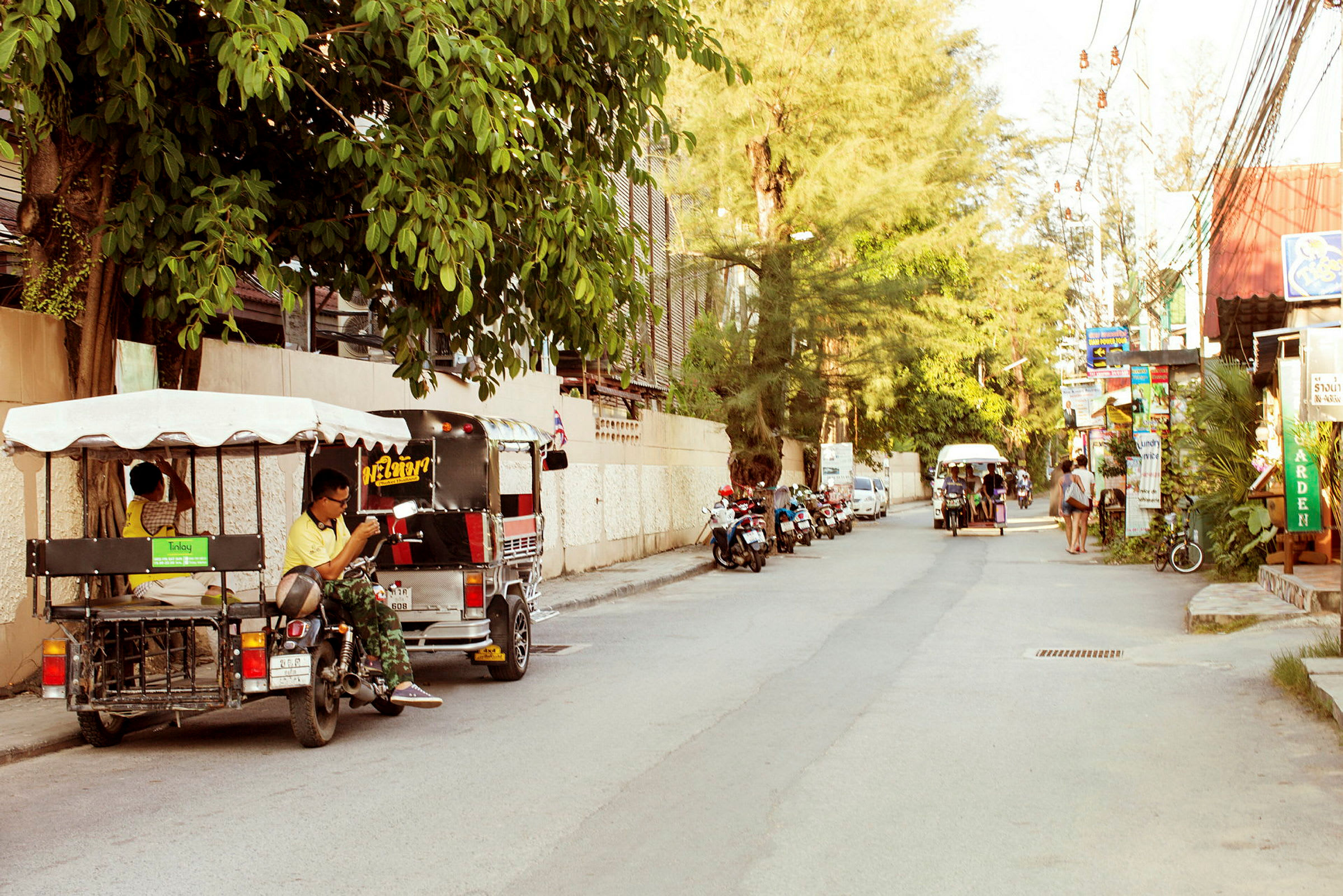 En gata med tuk-tuk-fordon och motorcyklar parkerade längs sidan. (AI-genererad text)