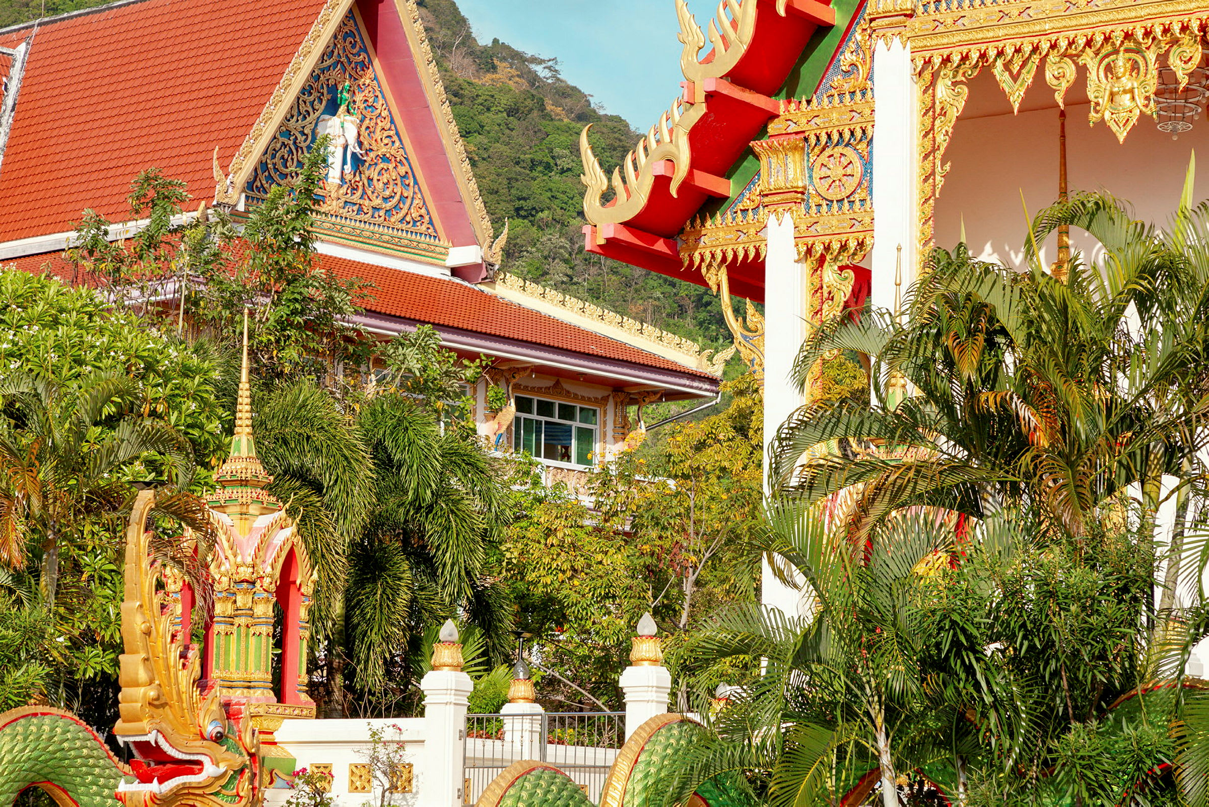 Bild av en traditionell thailändsk byggnad med dekorativa detaljer och omgiven av grönska. (AI-genererad text)