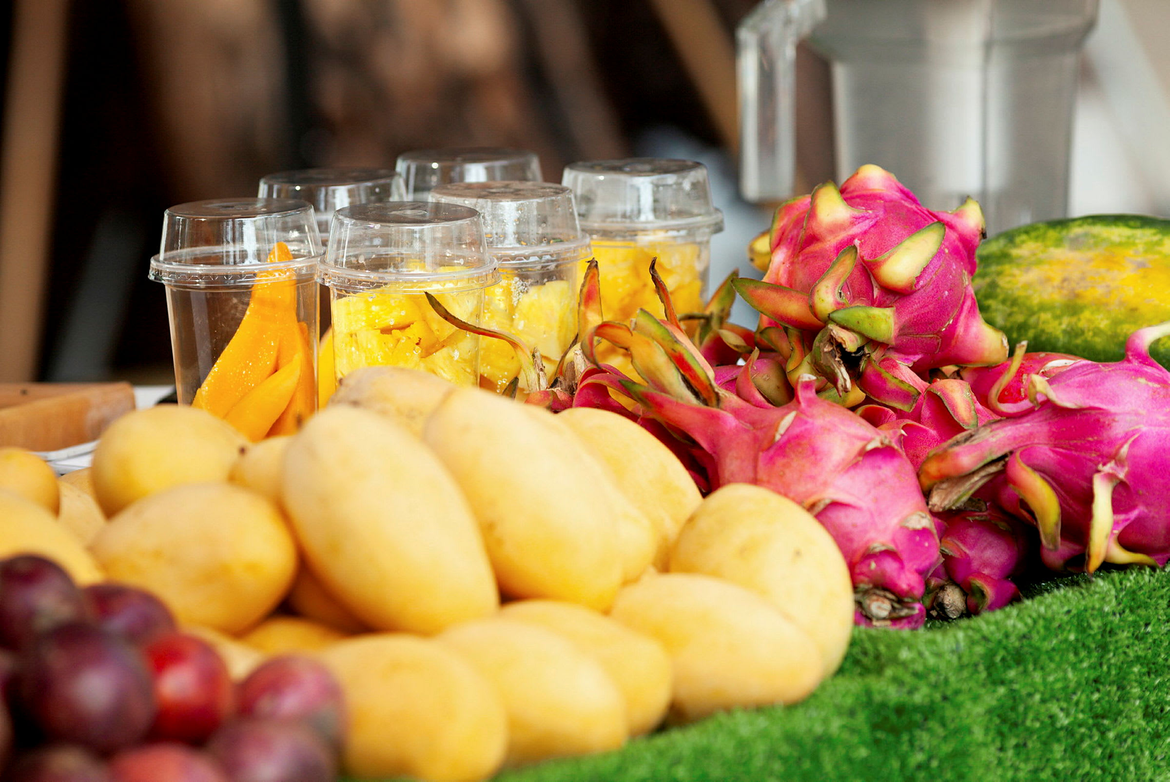 Färsk frukt, inklusive mango, drakfrukt och skivad frukt i plastbägare. (AI-genererad text)