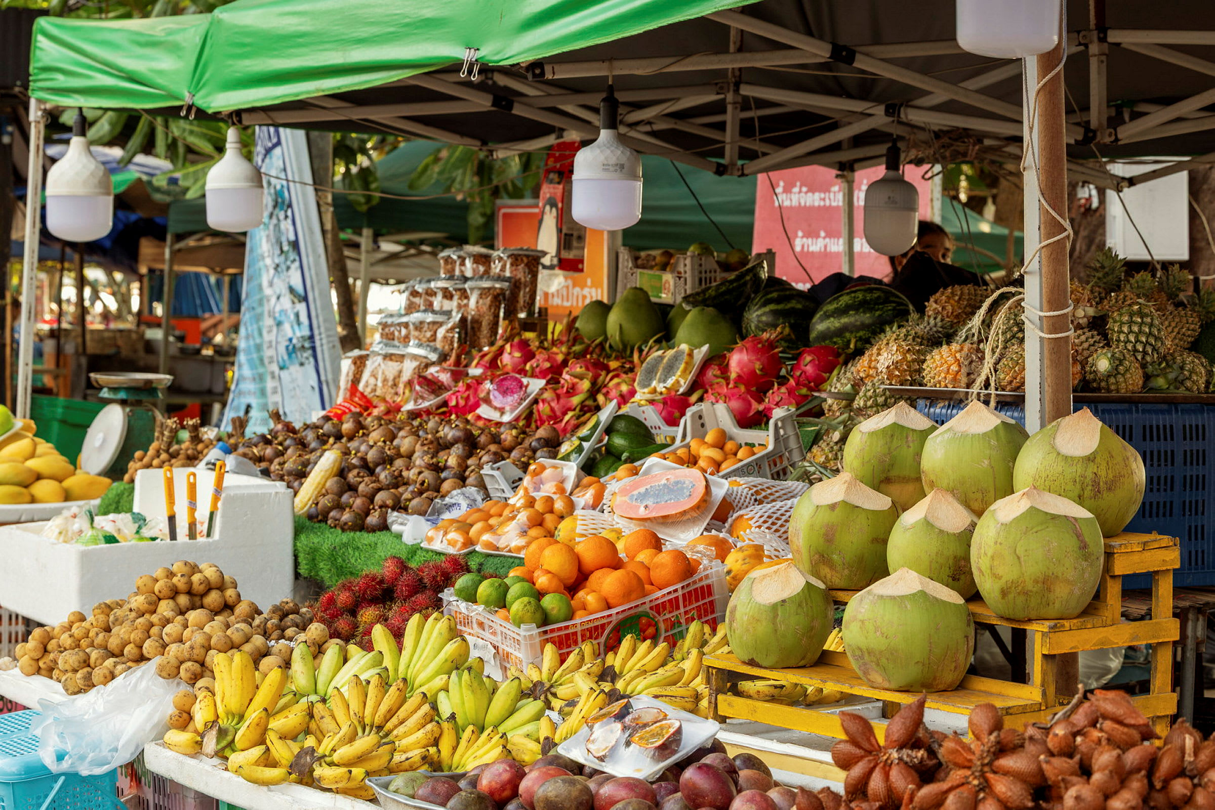 Marknadsstånd med ett stort utbud av tropiska frukter inklusive bananer, kokosnötter och mangostan. (AI-genererad text)