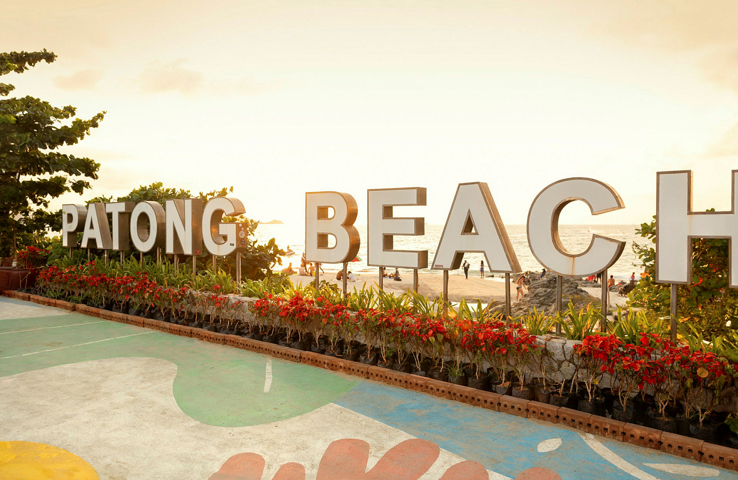 Skylt med texten 'Patong Beach' framför stranden. (AI-genererad text)