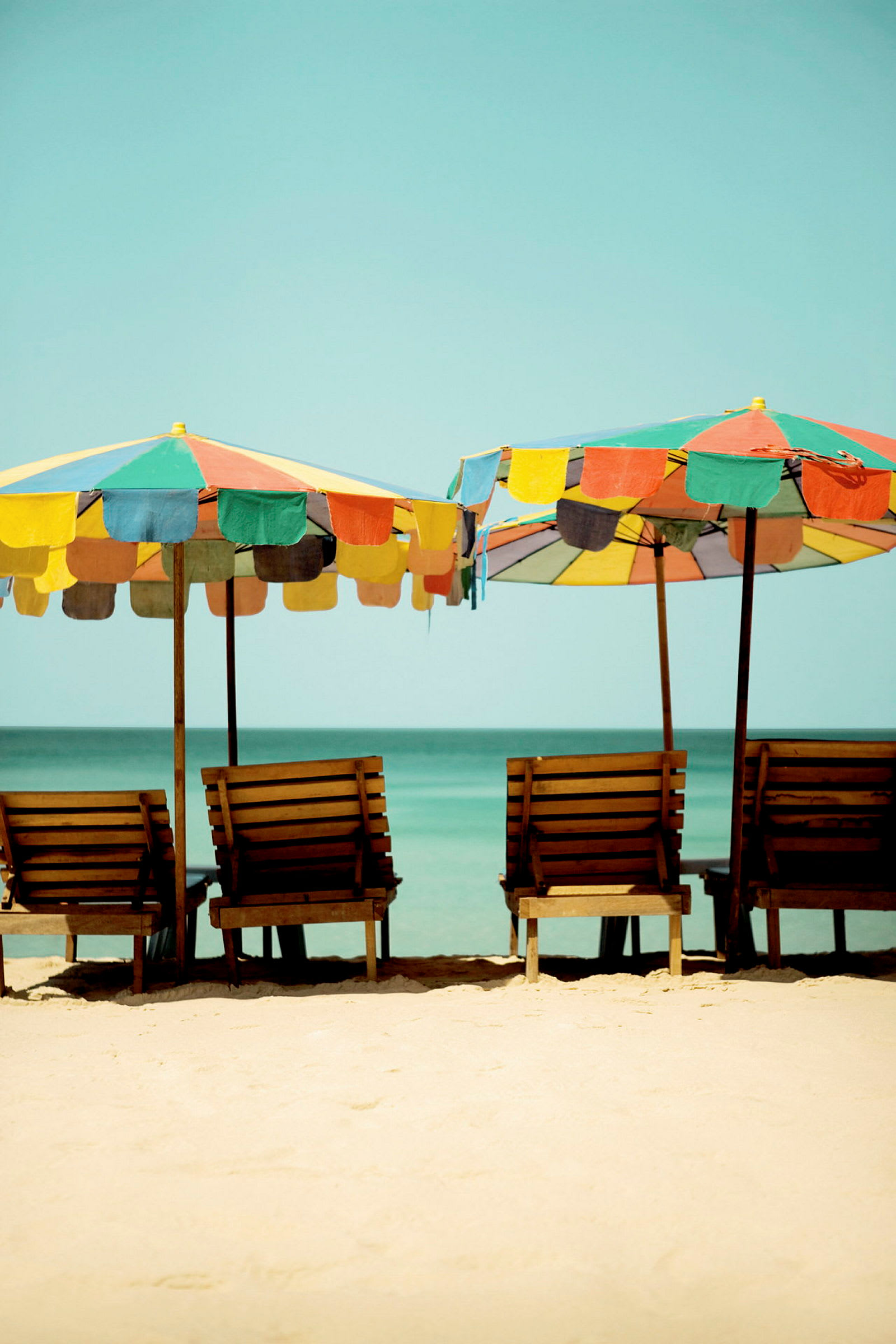 Strand med solstolar och färgade parasoller. (AI-genererad text)