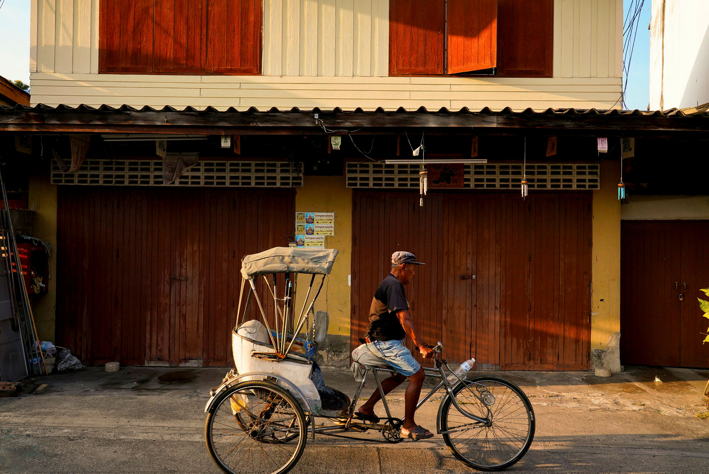 En cykelrickshaw framför en byggnad med mörka träportar. (AI-genererad text)