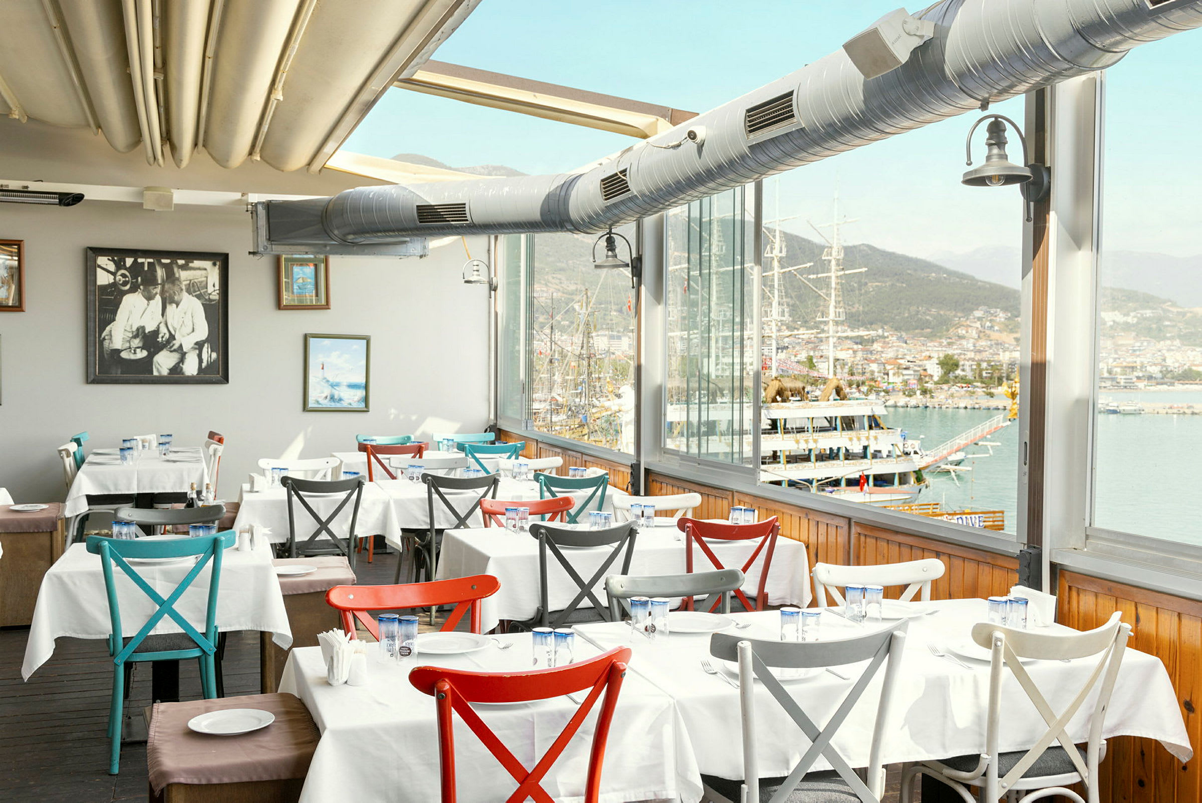 Interiör av en restaurang med dukade bord och utsikt över hamnen. (AI-genererad text)