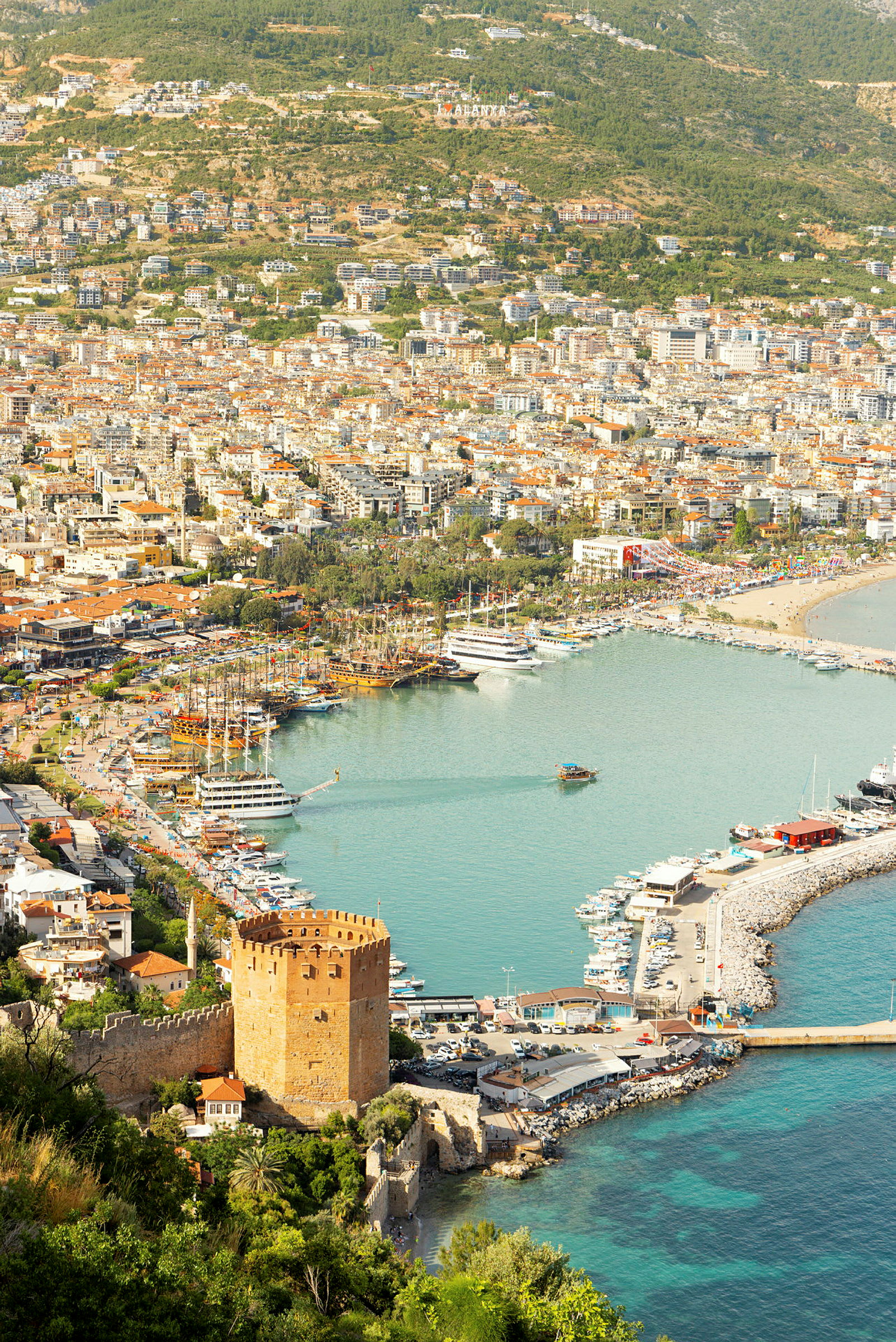 Utsikt över hamn och staden Alanya med en historisk röd byggnad i framkant. (AI-genererad text)