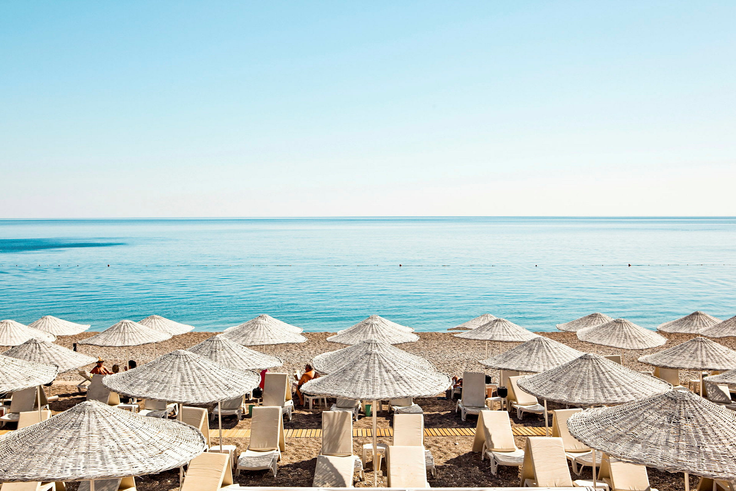 Solstolar och parasoller på en strand med havet i bakgrunden. (AI-genererad text)