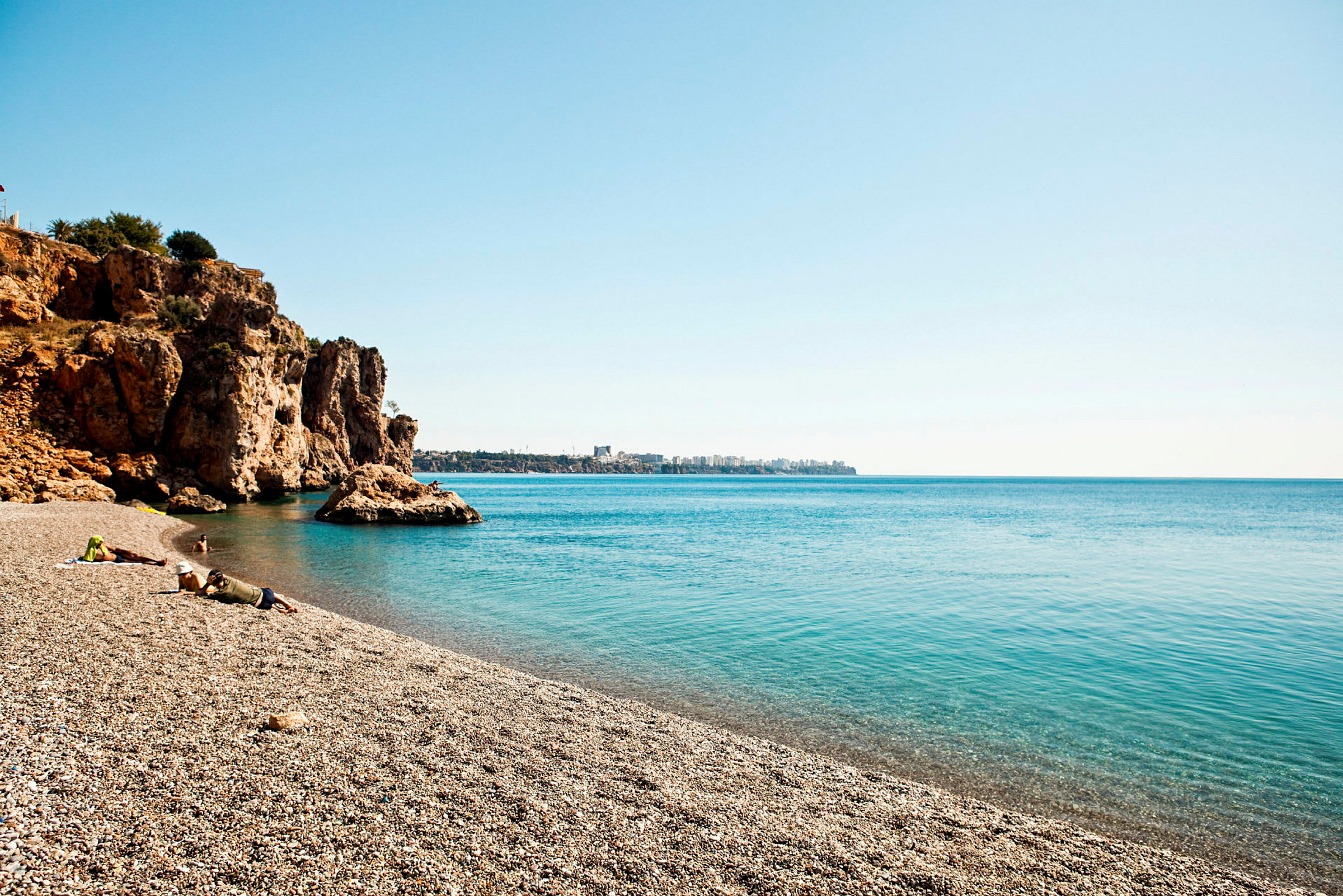 Sandstrand med klippor vid havet under klar himmel. (AI-genererad text)