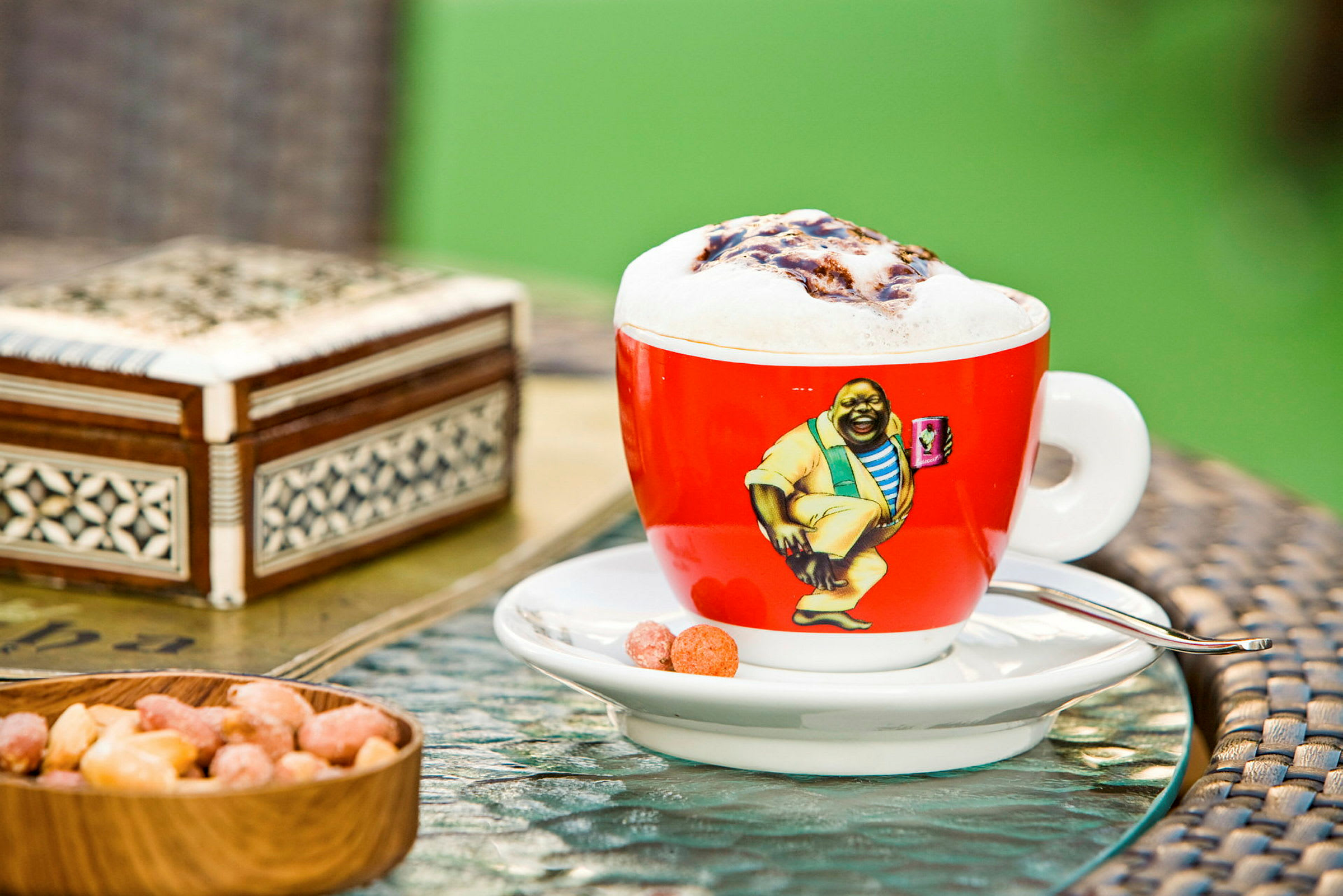 En kopp kaffe med skummat mjölk på ett bord tillsammans med några snacks. (AI-genererad text)