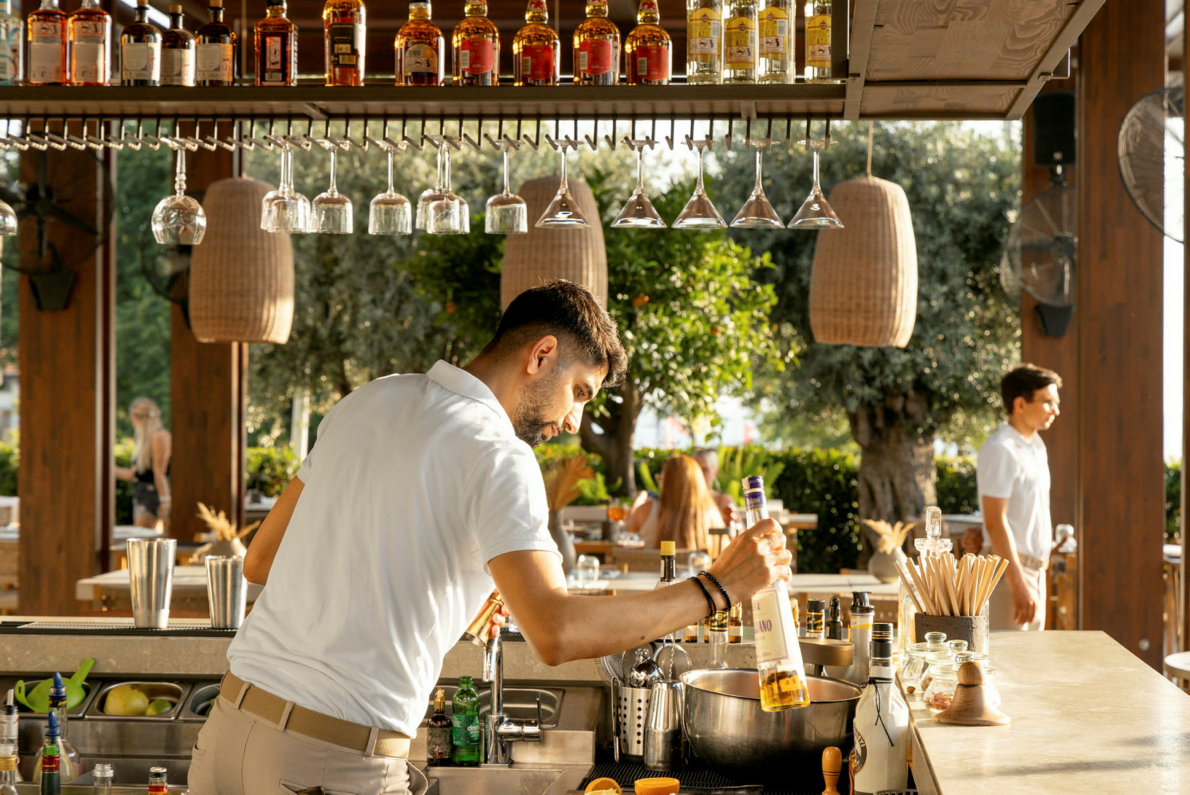 En bartender vid en utomhusbar räcker ut efter en flaska sprit. (AI-genererad text)