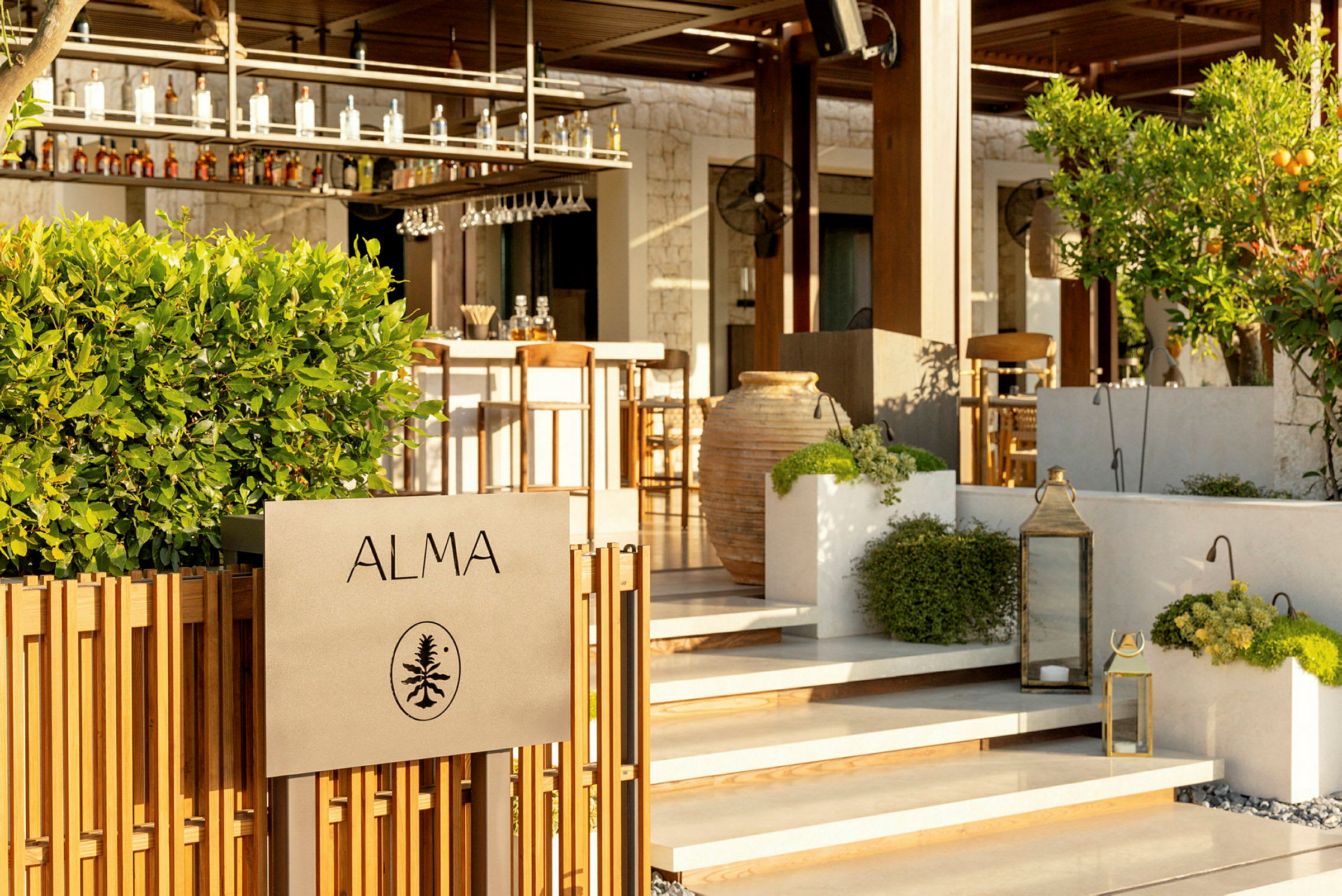 Skylt med texten "ALMA" framför en bar med grönska och dekorationer. (AI-genererad text)