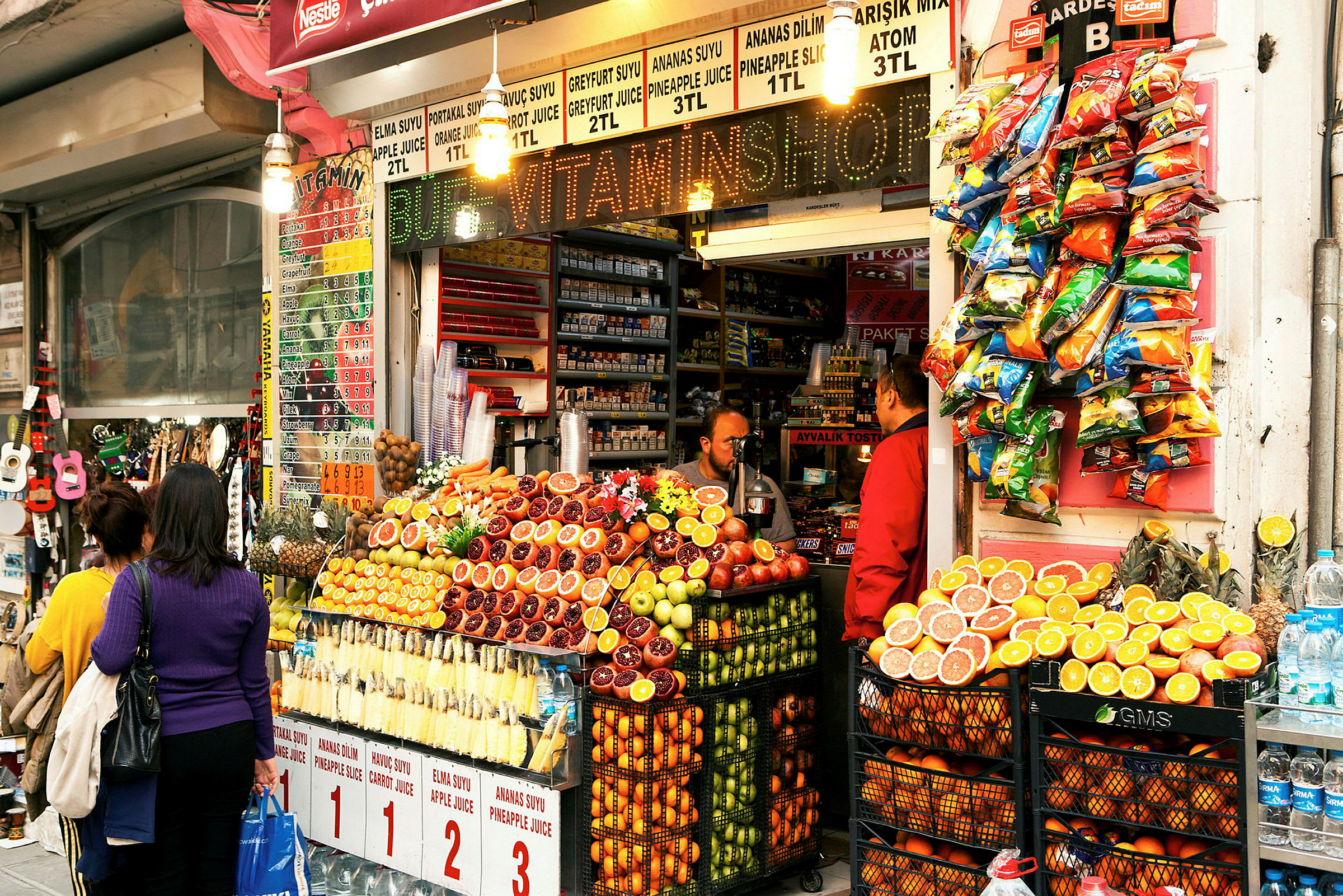 En fruktstånd framför en butik, med färska frukter och juicer. (AI-genererad text)
