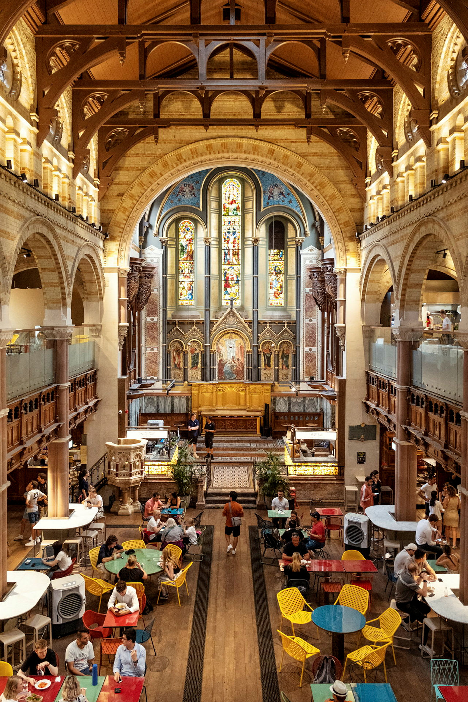 En interiör av en kyrka med färgade glasfönster och ett kaféområde. (AI-genererad text)