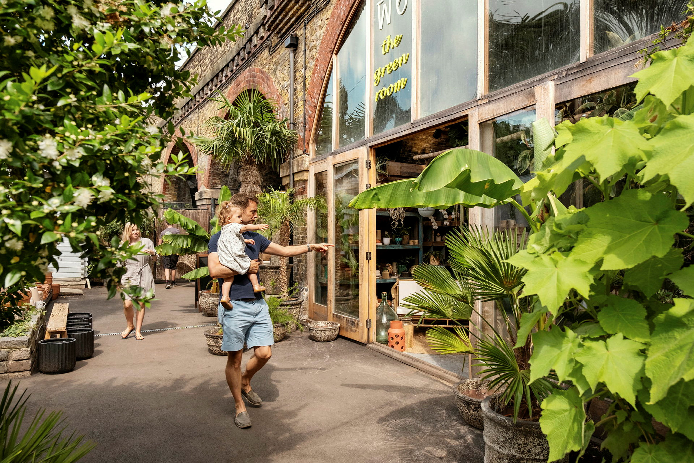 En man som håller i ett barn framför en butik med växtdekorationer. (AI-genererad text)