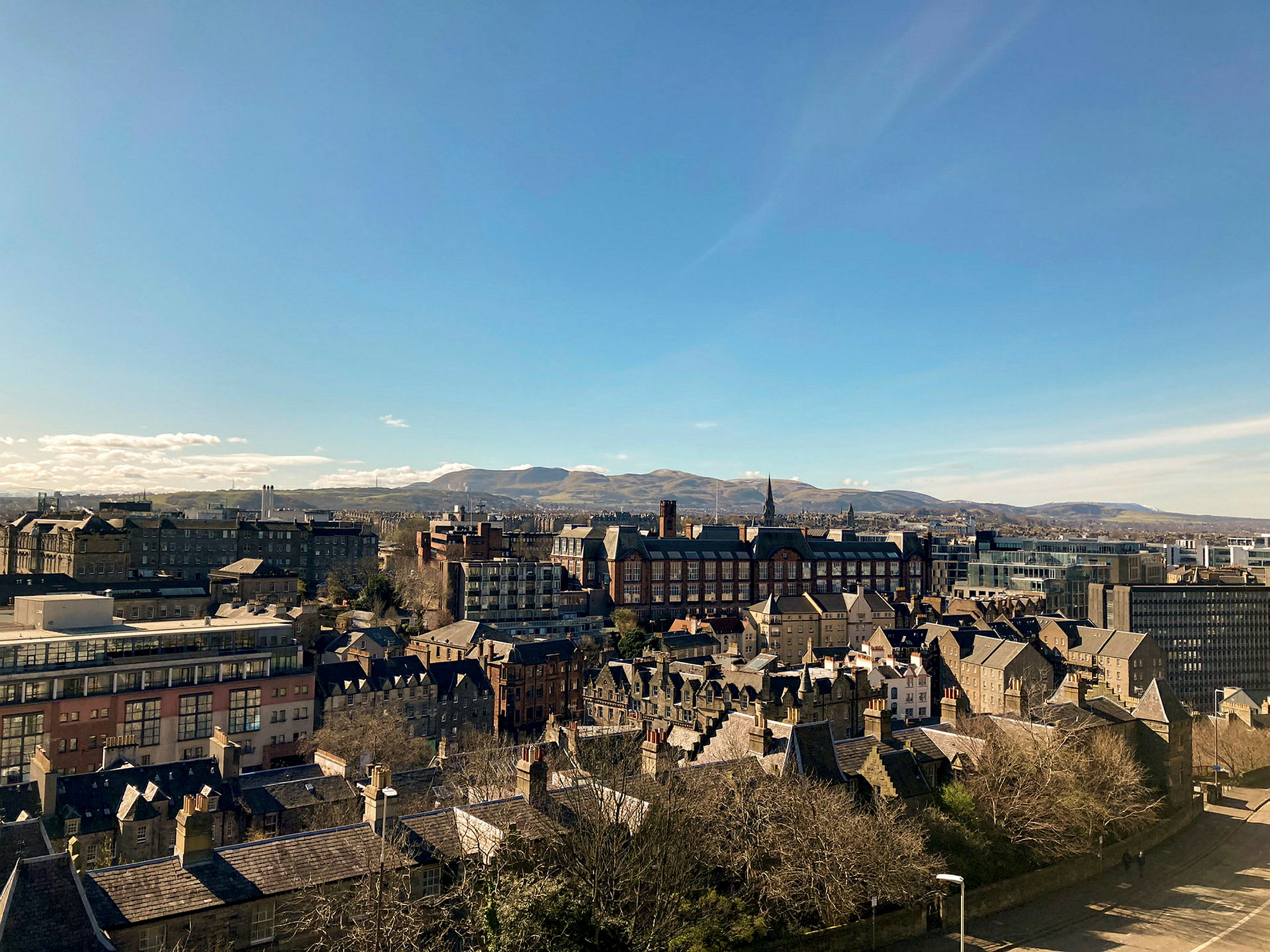 Stadsvy med byggnader och berg i bakgrunden. (AI-genererad text)