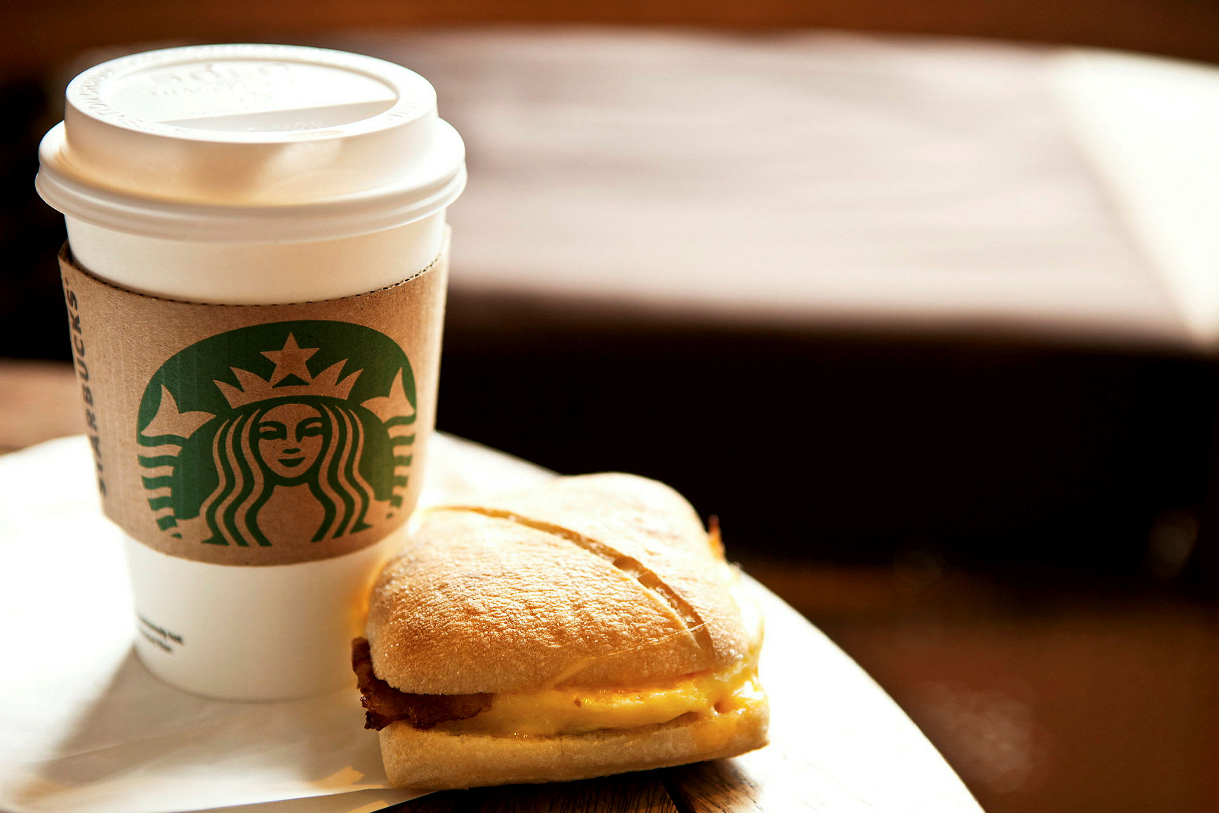 En kopp med kaffe och en smörgås på ett bord. (AI-genererad text)