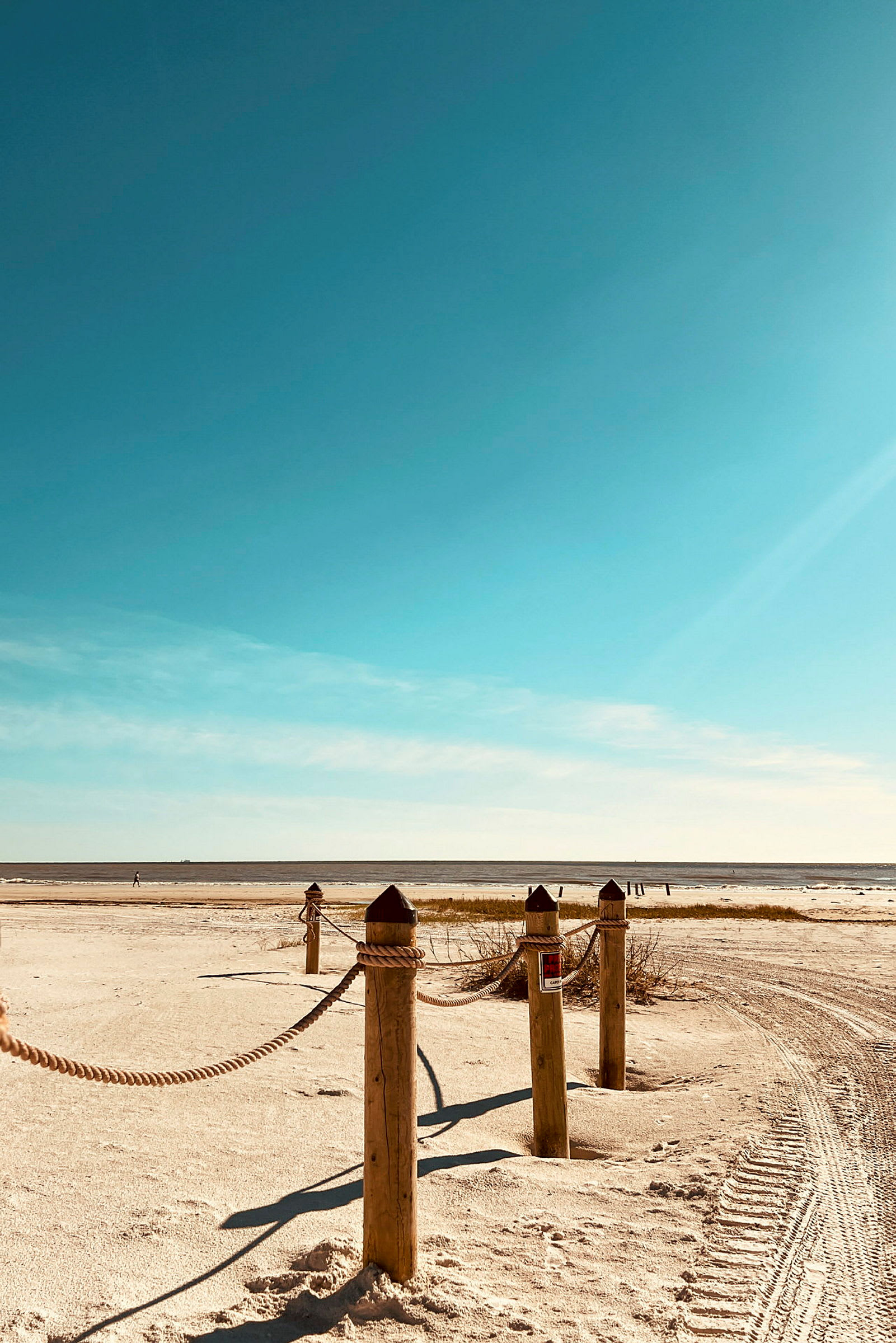 Trästolpar med rep vid en strand. (AI-genererad text)
