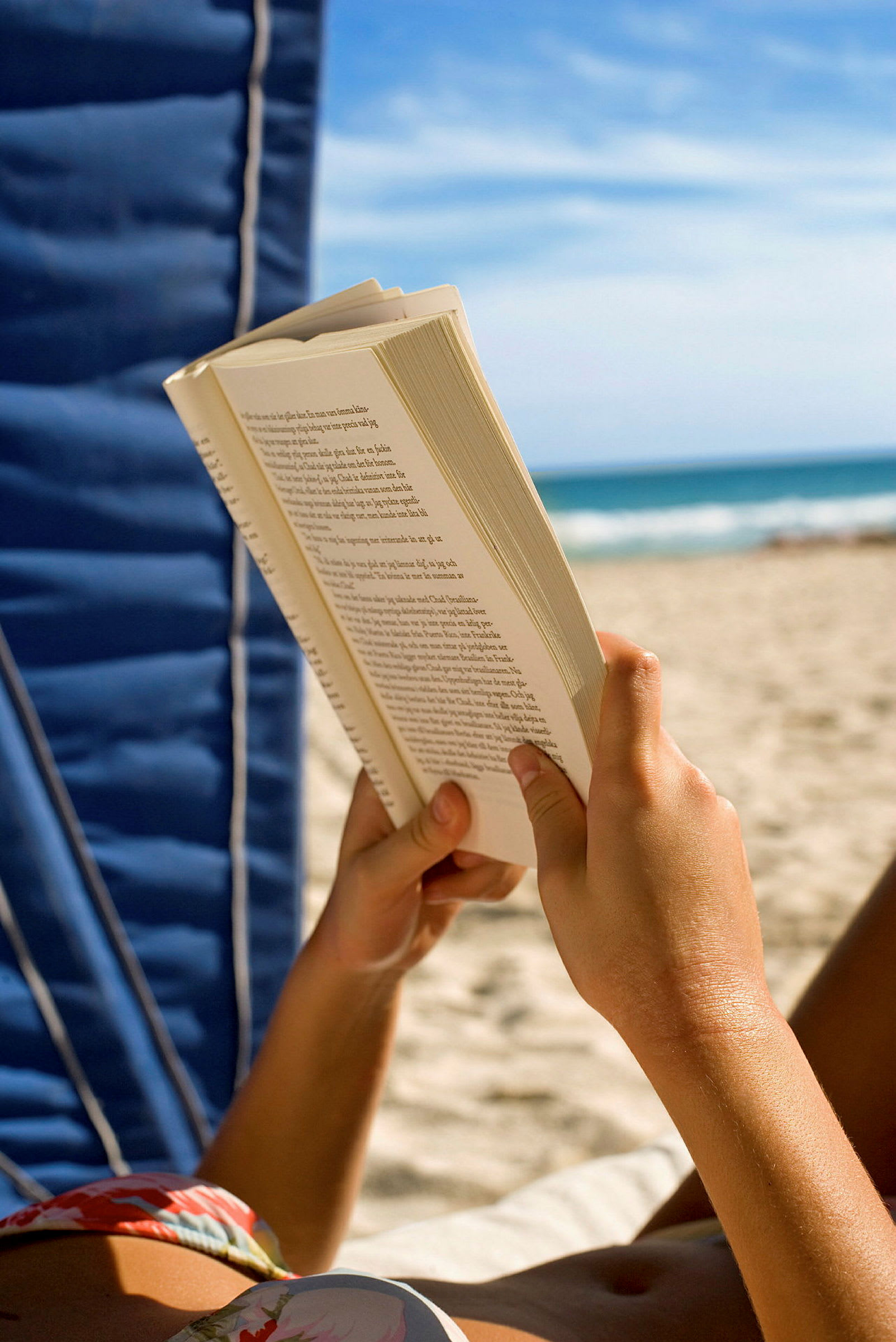 En person läser en bok på en strand. (AI-genererad text)