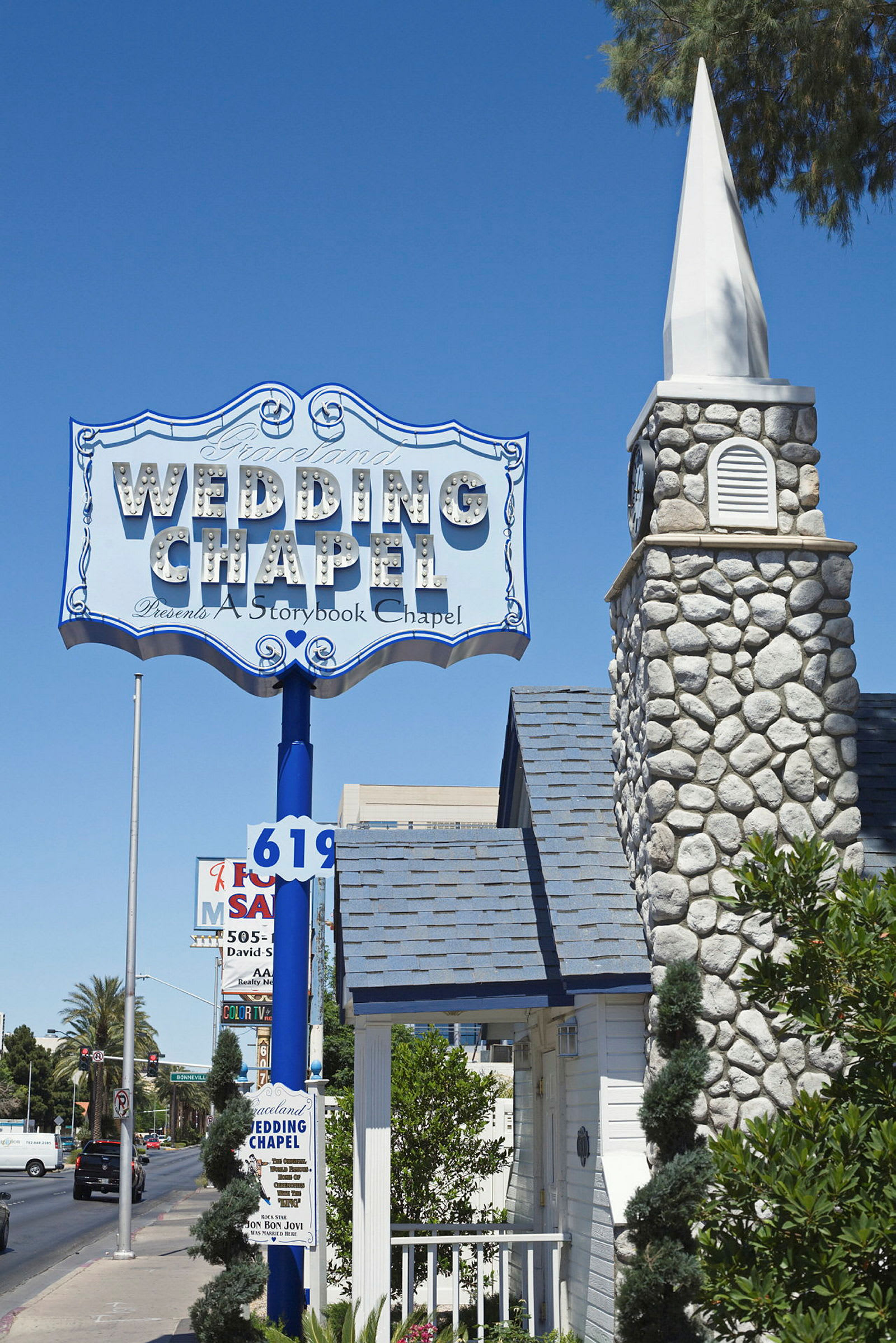 En skylt med texten 'Wedding Chapel' ovanför en stenkyrkas byggnad, med en blå himmel i bakgrunden. (AI-genererad text)